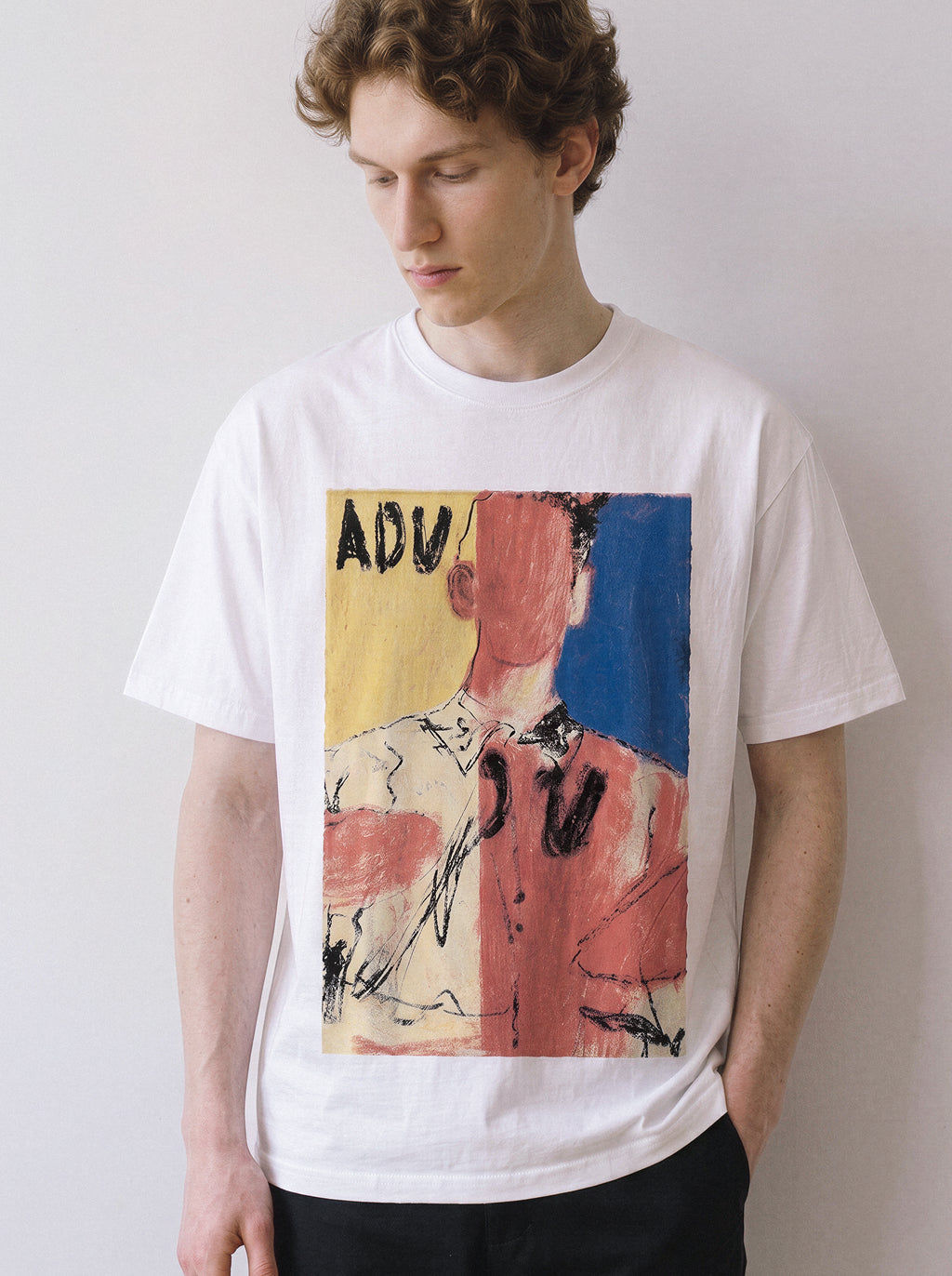 A male model looking down wearing a white abstract faceless portrait graphic tee, highlighting the heavy oil-pastel strokes and relaxed streetwear fit.