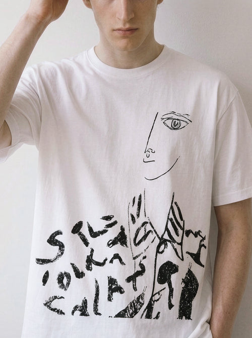 A white short-sleeve crewneck t-shirt featuring a black line art graphic of a face and abstract text, worn by a model against a plain light background.