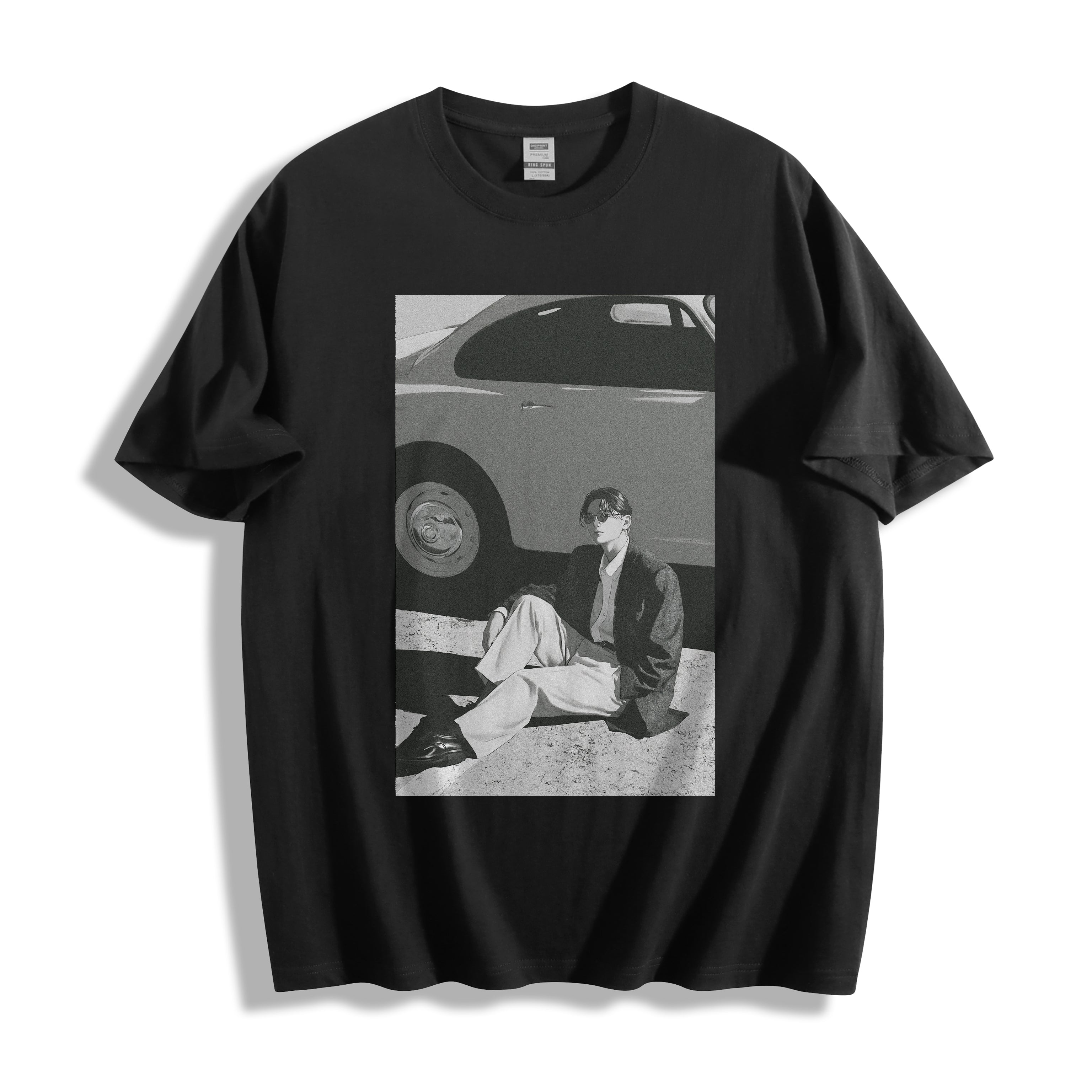 A black short-sleeve crewneck t-shirt with a 90s retro black and white photography print on the front, showing a vintage car and a seated person, displayed against a clean white background.