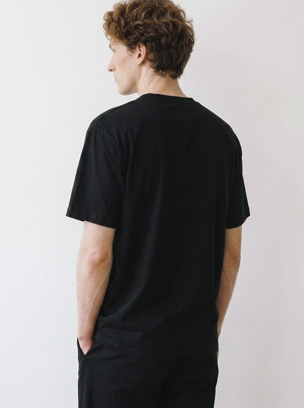 Back view of a male model demonstrating the comfortable, relaxed fit of a black oversized graphic t-shirt.