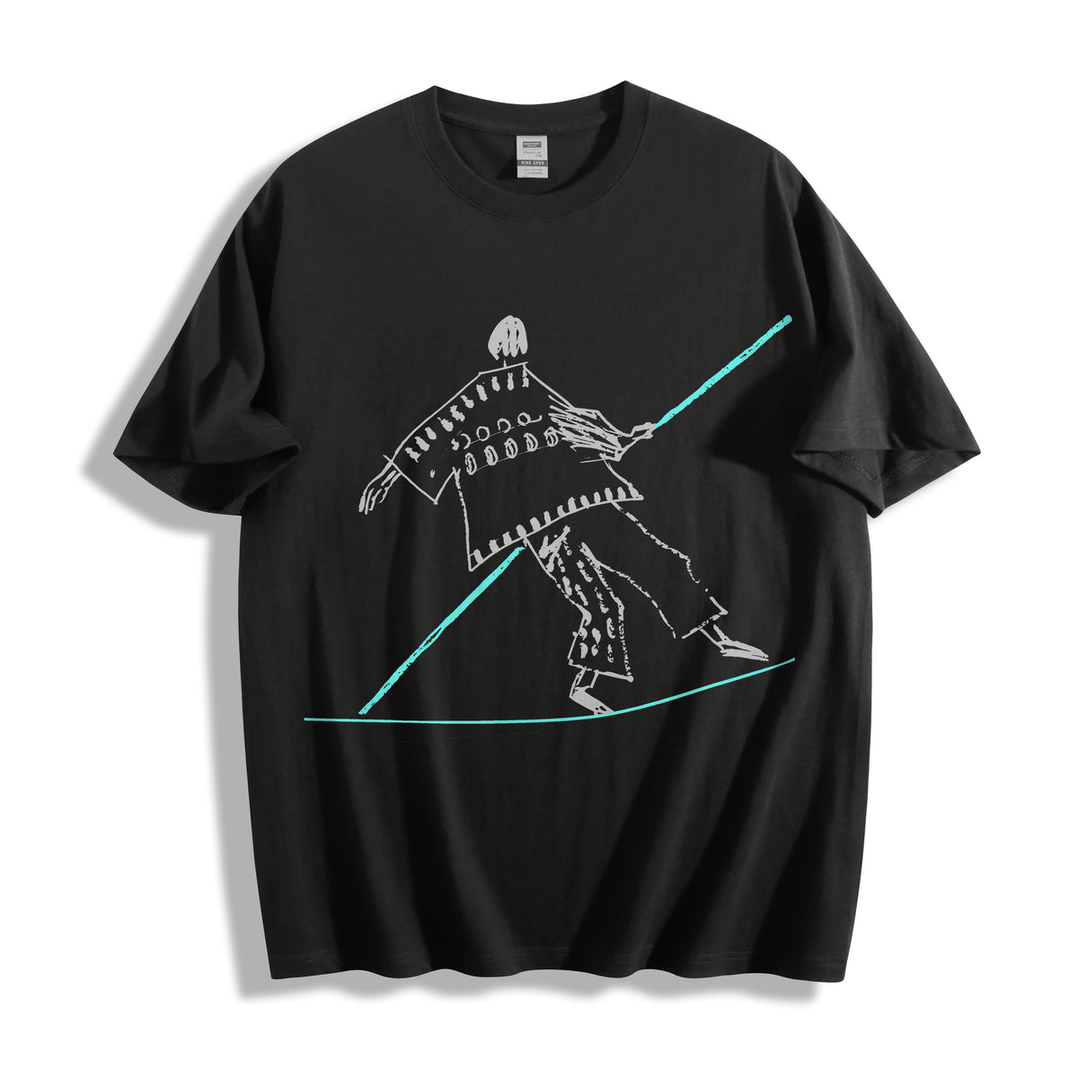 Top-down flat lay view of a black oversized streetwear t-shirt displaying a striking minimalist tightrope walker balancing on a high wire.