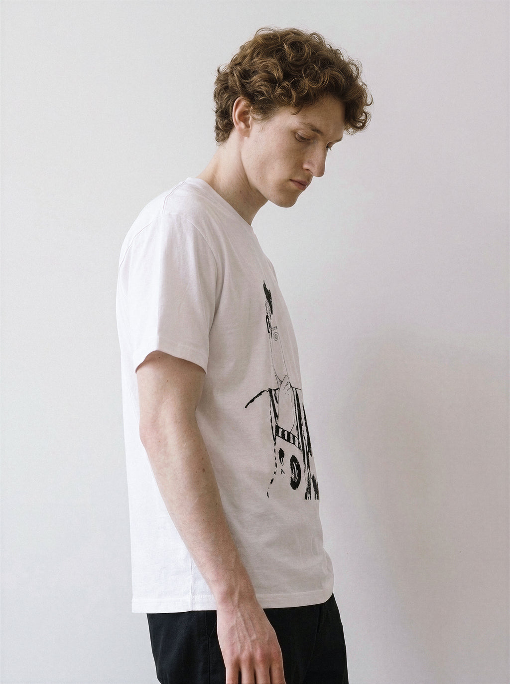 A side profile of a male model looking down wearing a white blank stare portrait line art graphic tee, emphasizing the independent manga aesthetic.