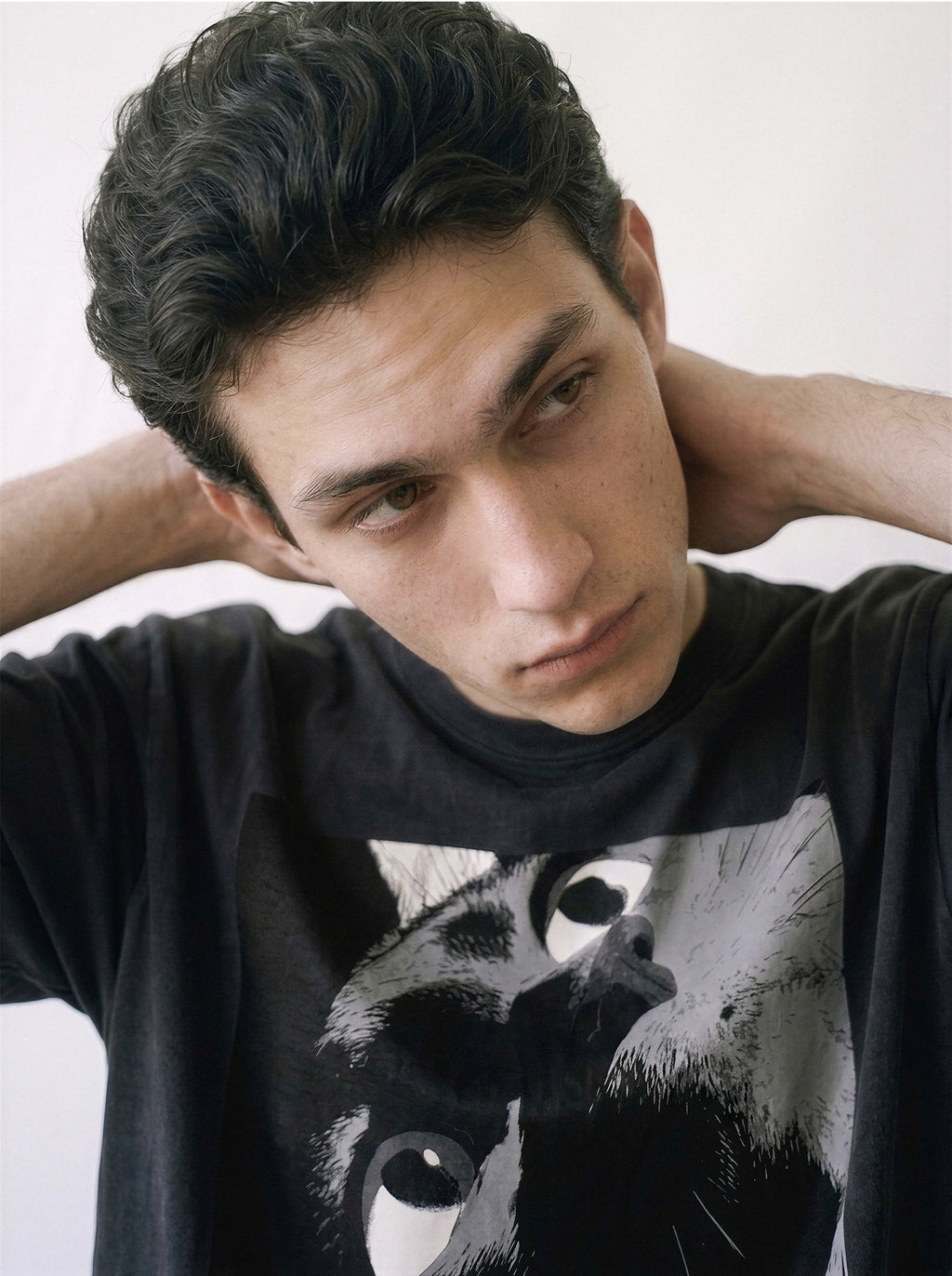 A close-up of a male model looking down wearing a black cat gaze manga panel graphic tee, highlighting the striking independent manga aesthetic.