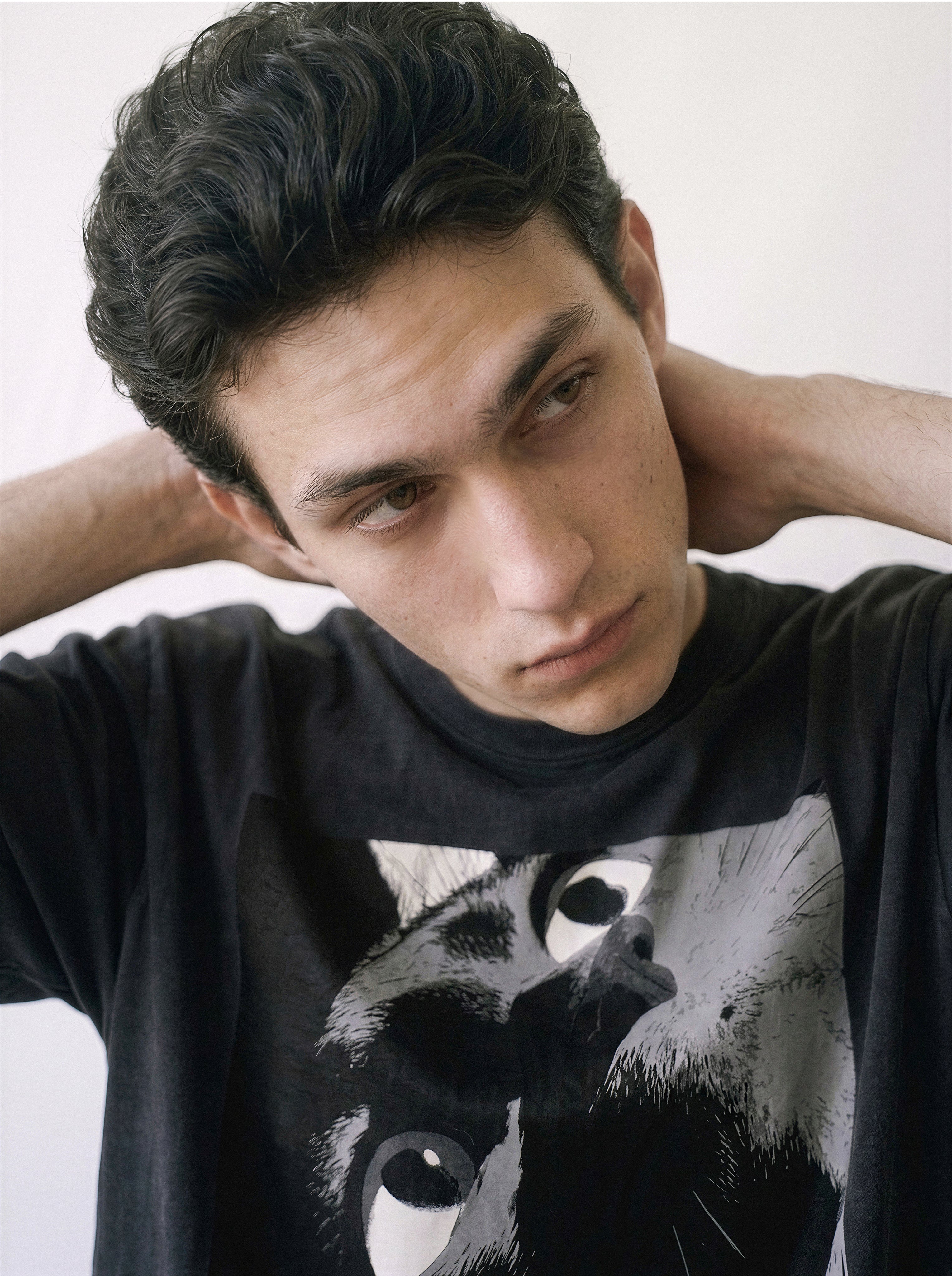 A close-up of a male model looking down wearing a black cat gaze manga panel graphic tee, highlighting the striking independent manga aesthetic.