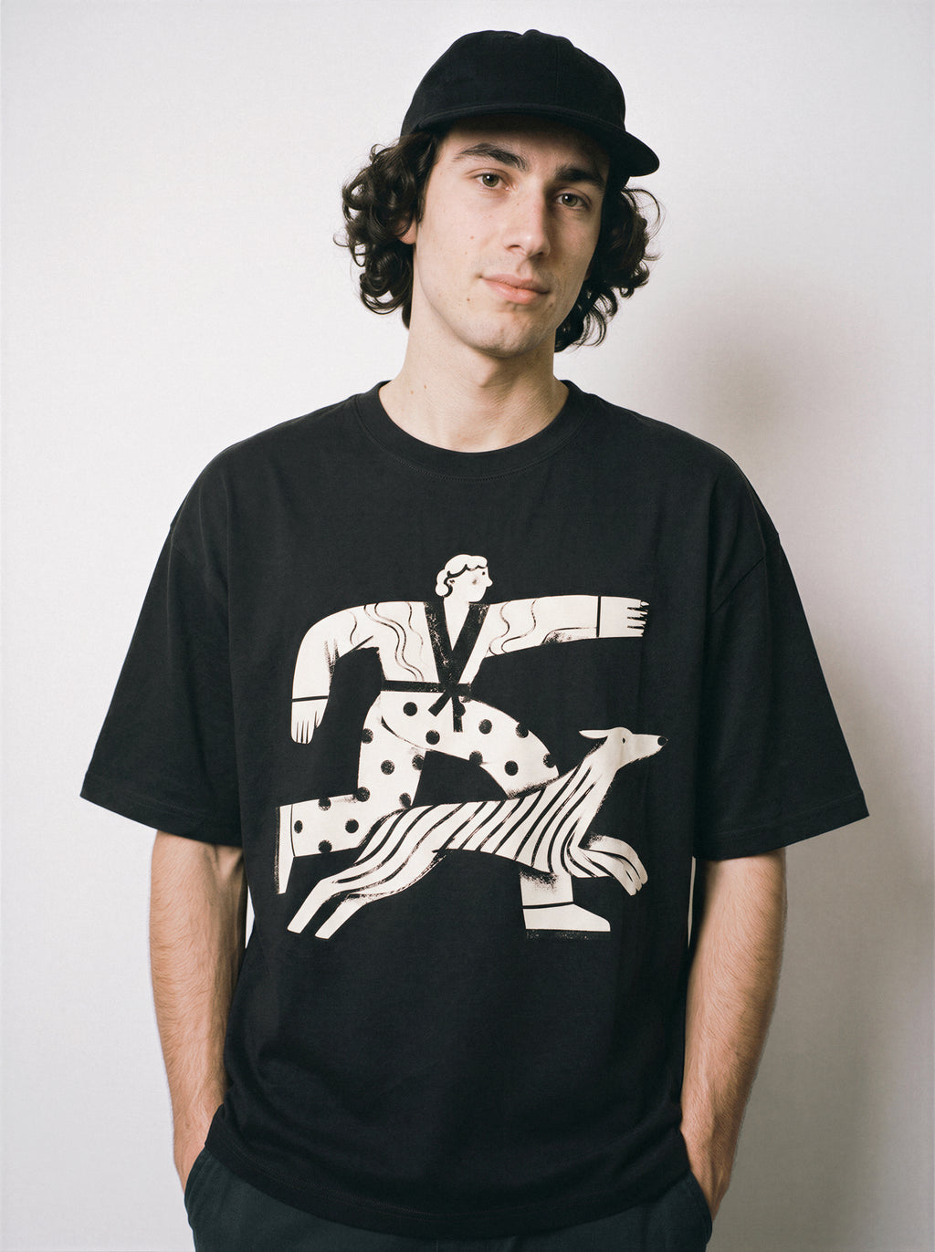 A front view of a male model wearing a black confident stride boy and dog graphic tee, highlighting the bold forward-moving aesthetic and confident mood.