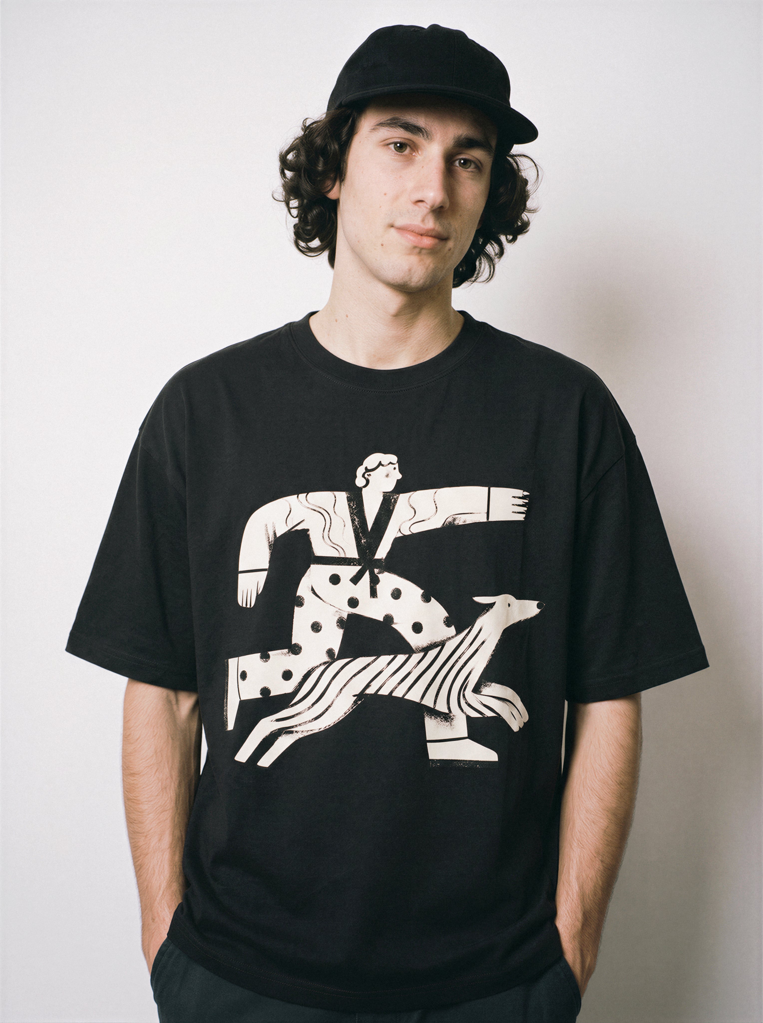 A front view of a male model wearing a black confident stride boy and dog graphic tee, highlighting the bold forward-moving aesthetic and confident mood.