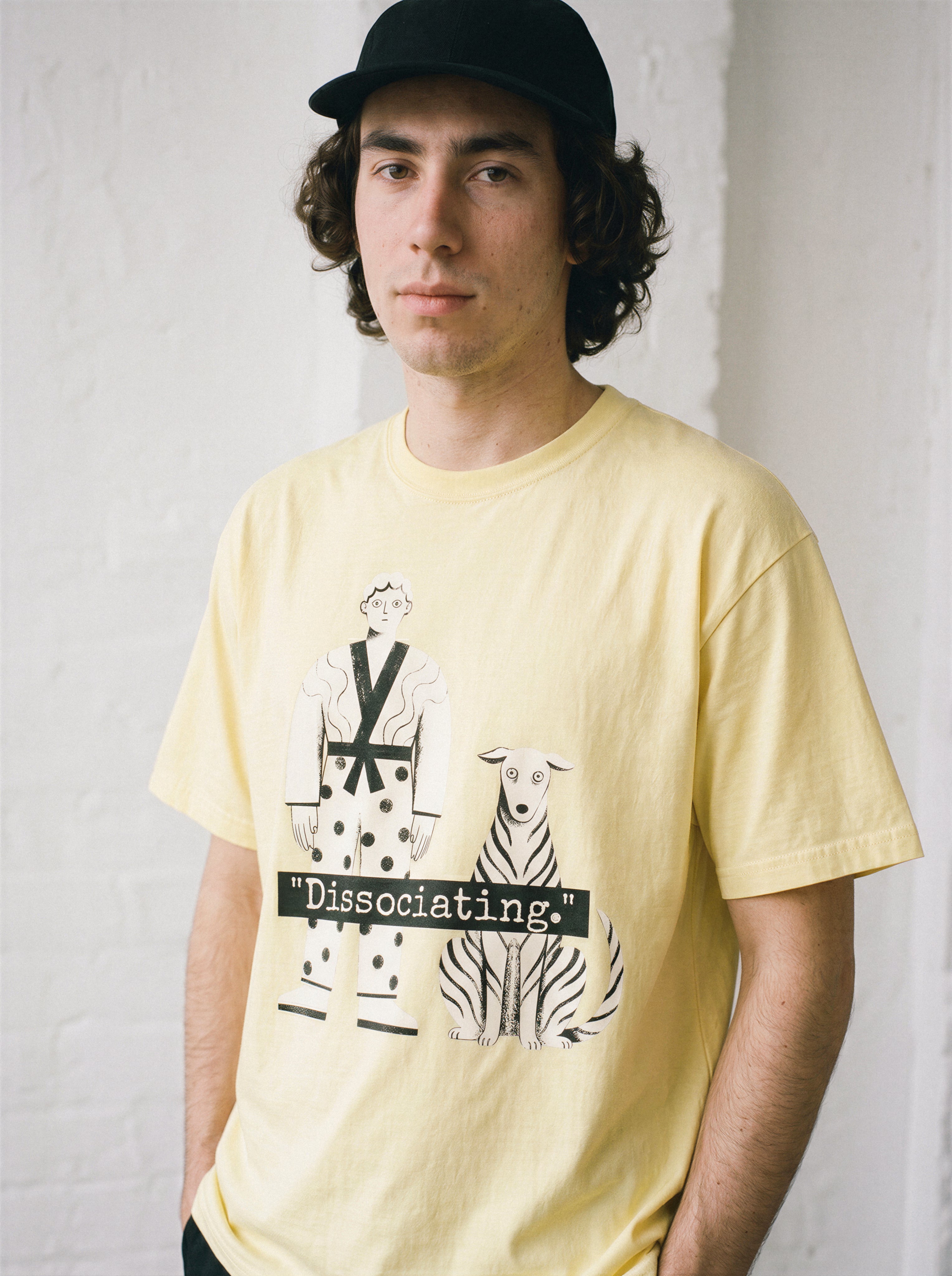 A male model standing straight wearing a butter dissociating line art graphic tee, emphasizing the doing absolutely nothing concept and relaxed boxy fit.