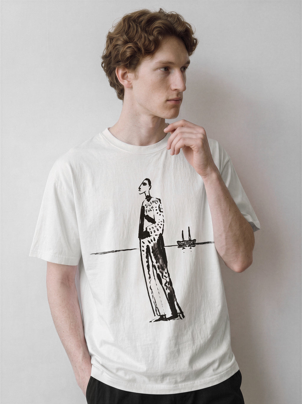 A male model posing casually wearing a white mysterious elongated figure line art graphic tee, emphasizing the pure line art form and indie art aesthetic.