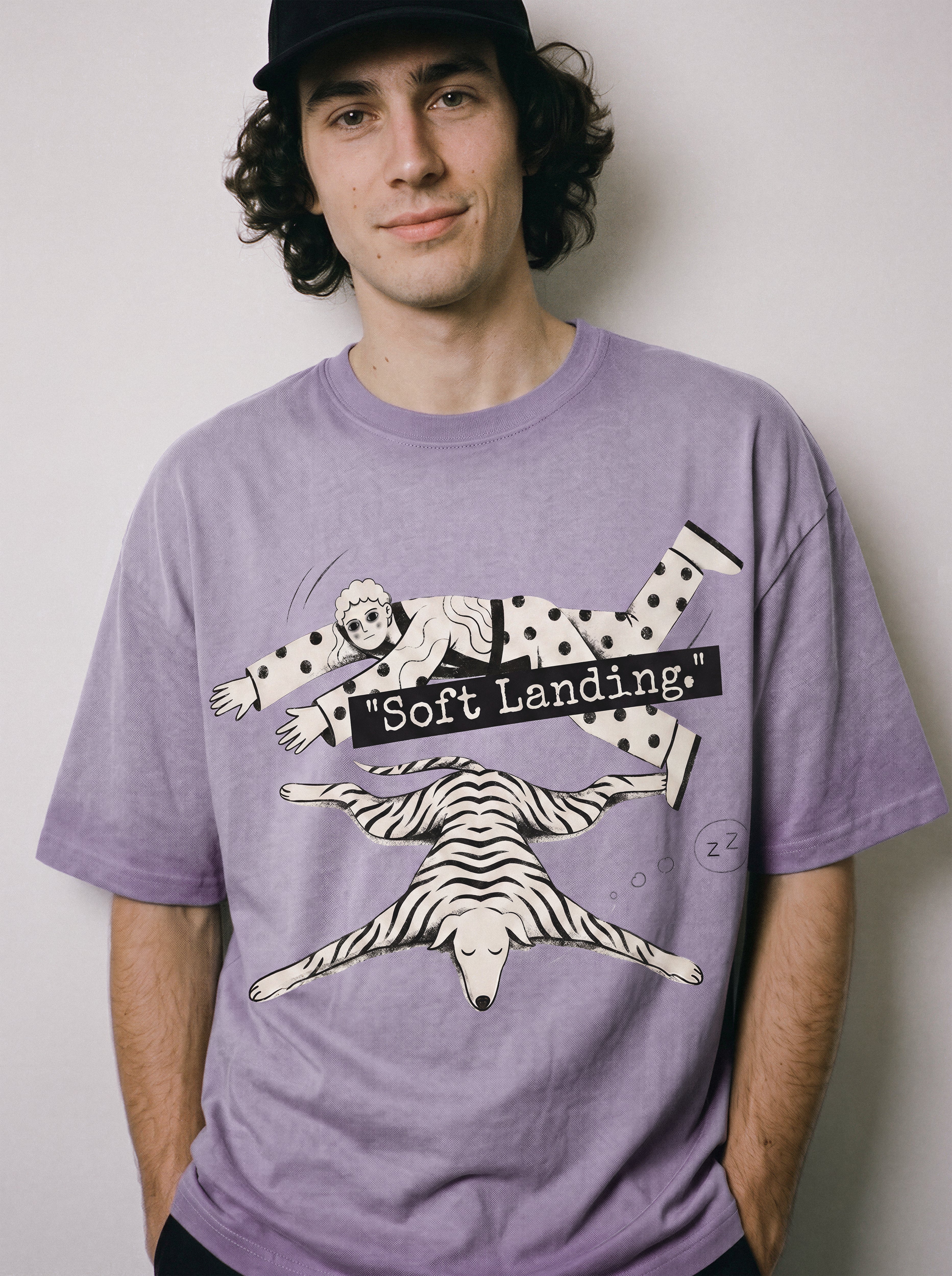 A male model with hands in his pockets wearing an ombre violet face down soft landing graphic tee, showcasing the existential streetwear vibe and lying flat print.