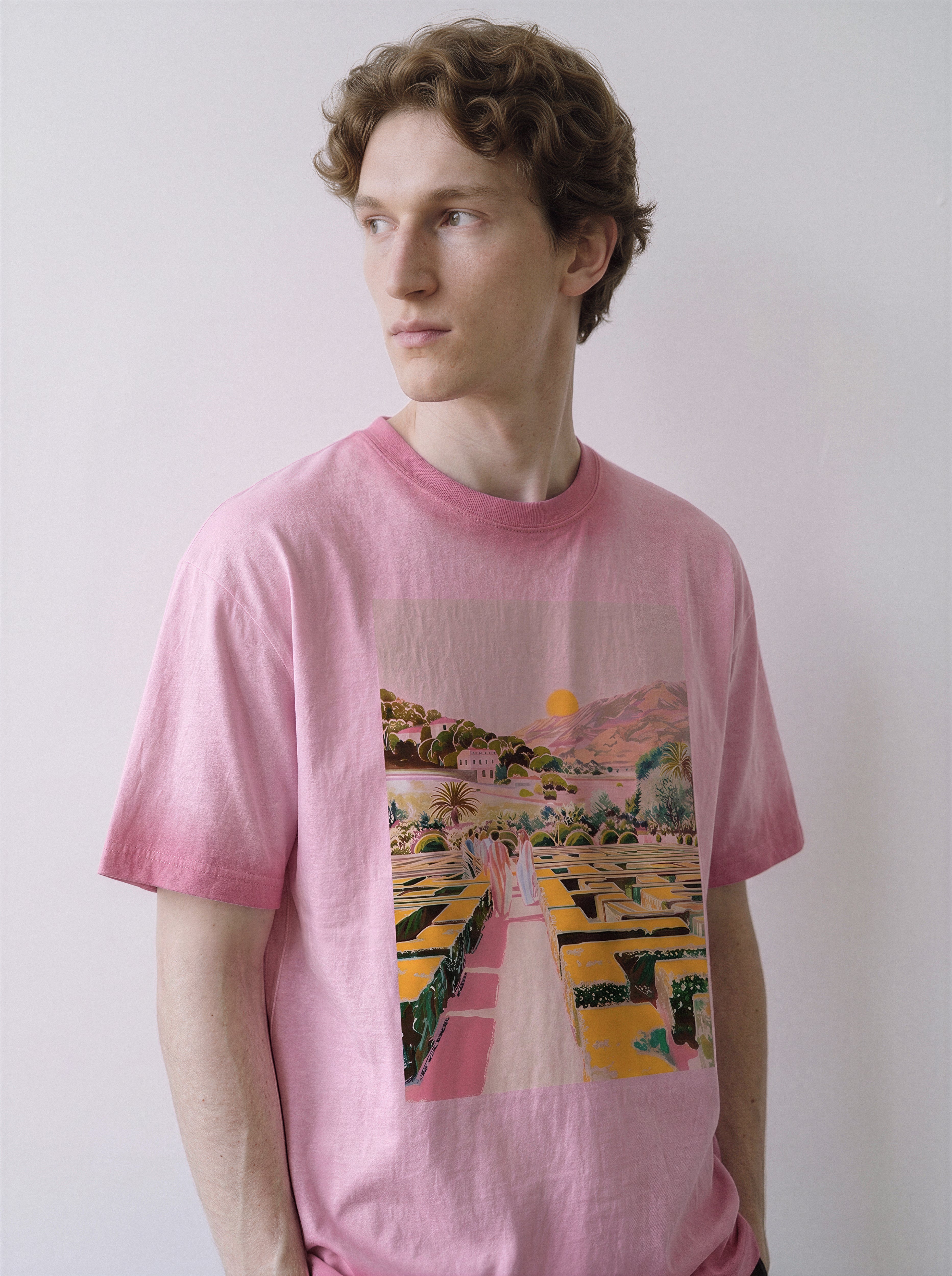 A male model looking to the left wearing an aura pink geometric labyrinth graphic novel tee, capturing the receding figures print and deceptive tranquil atmosphere.