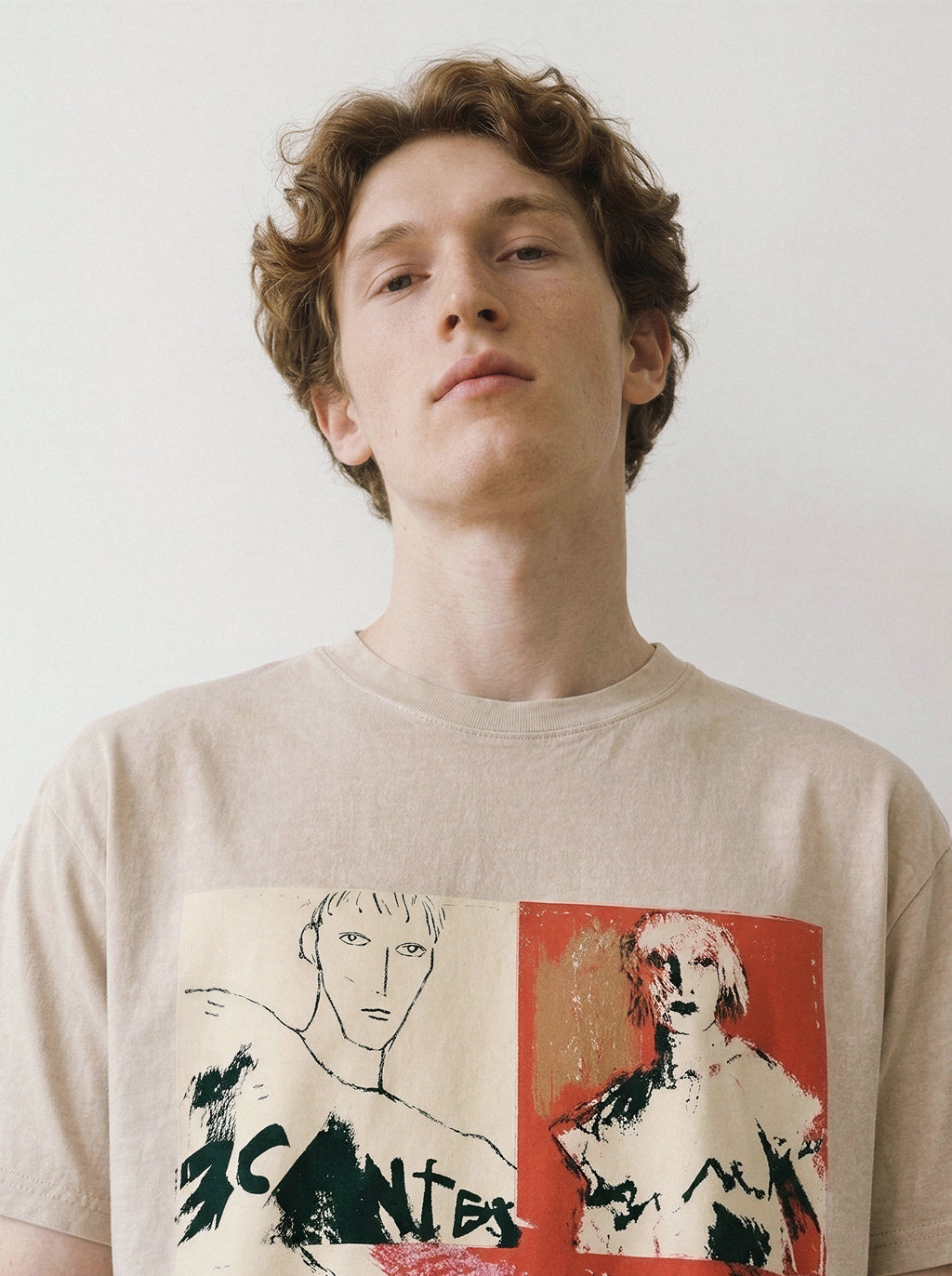 A front view of a male model looking slightly up wearing a mineral sand handshake portrait mixed media graphic tee, emphasizing the heavy screenprint textures and raw artistic attitude.