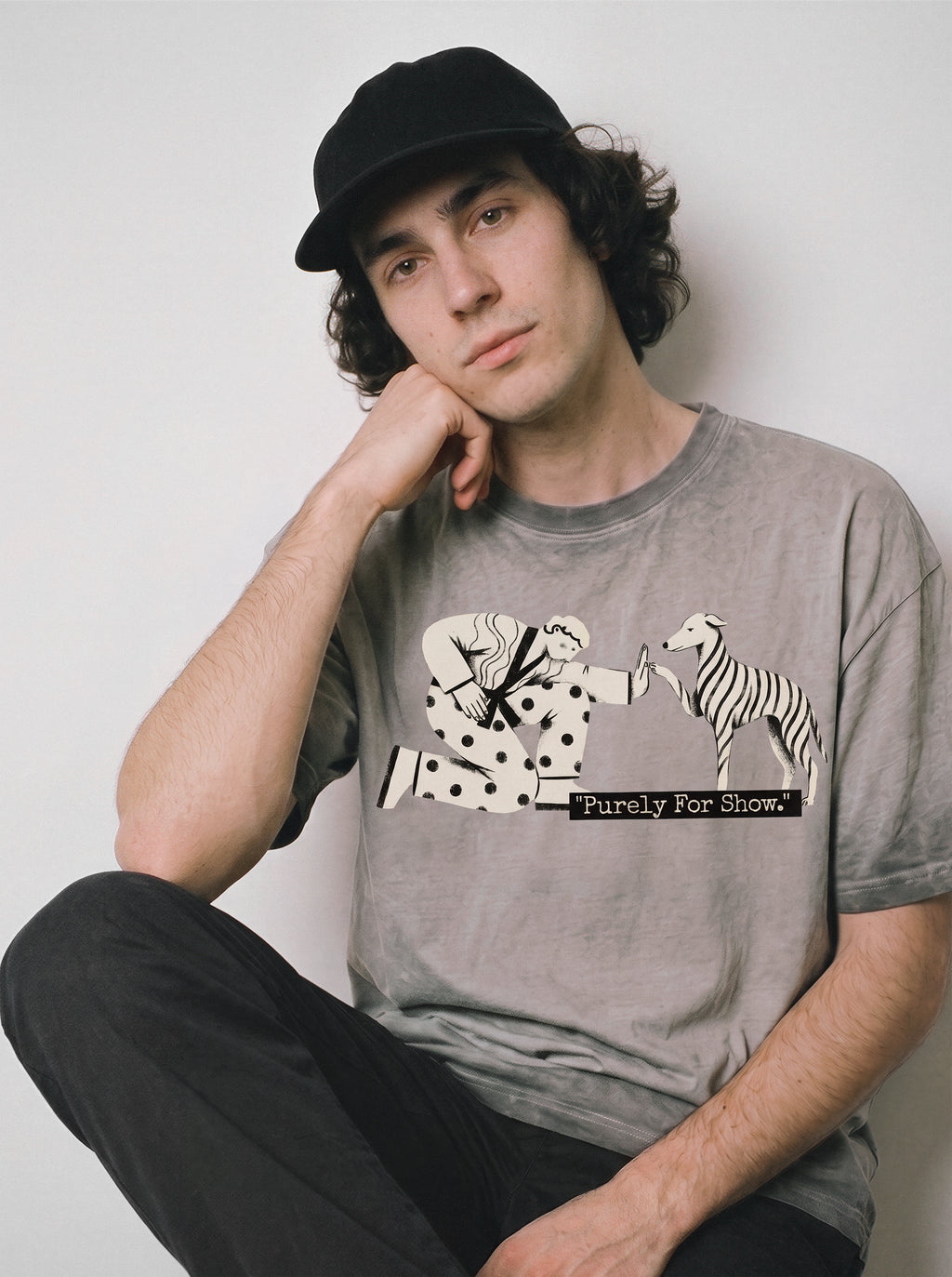 A seated male model resting his head on his hand wearing an ombre grey ironic high five graphic tee, highlighting the relatable going through the motions mood.