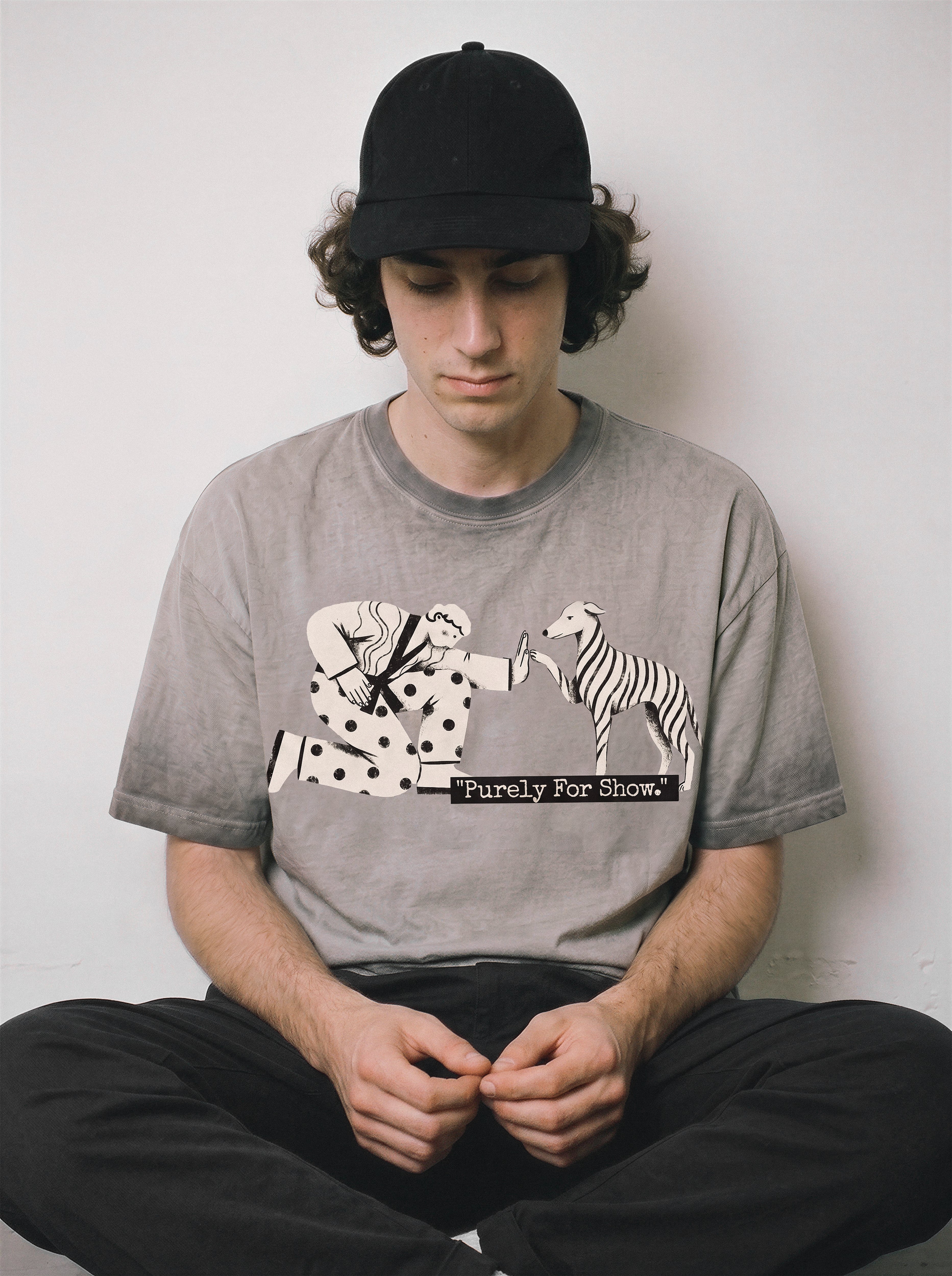 A seated male model looking down wearing an ombre grey ironic high five graphic tee, displaying the casual drape and quirky mental health humor style.