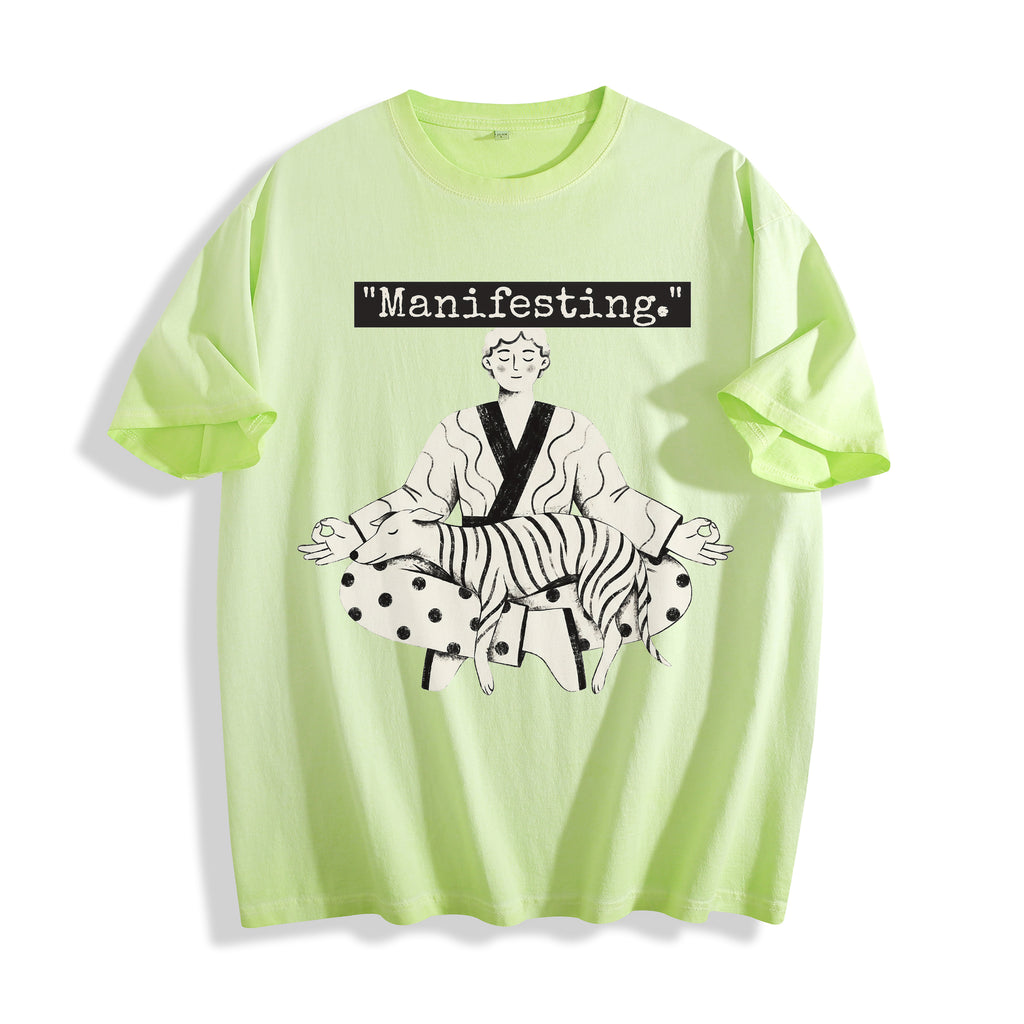 A flat lay of an acid lime manifesting meditating graphic tee, featuring the deadpan boy and dog line art print depicting a detached state of mind.