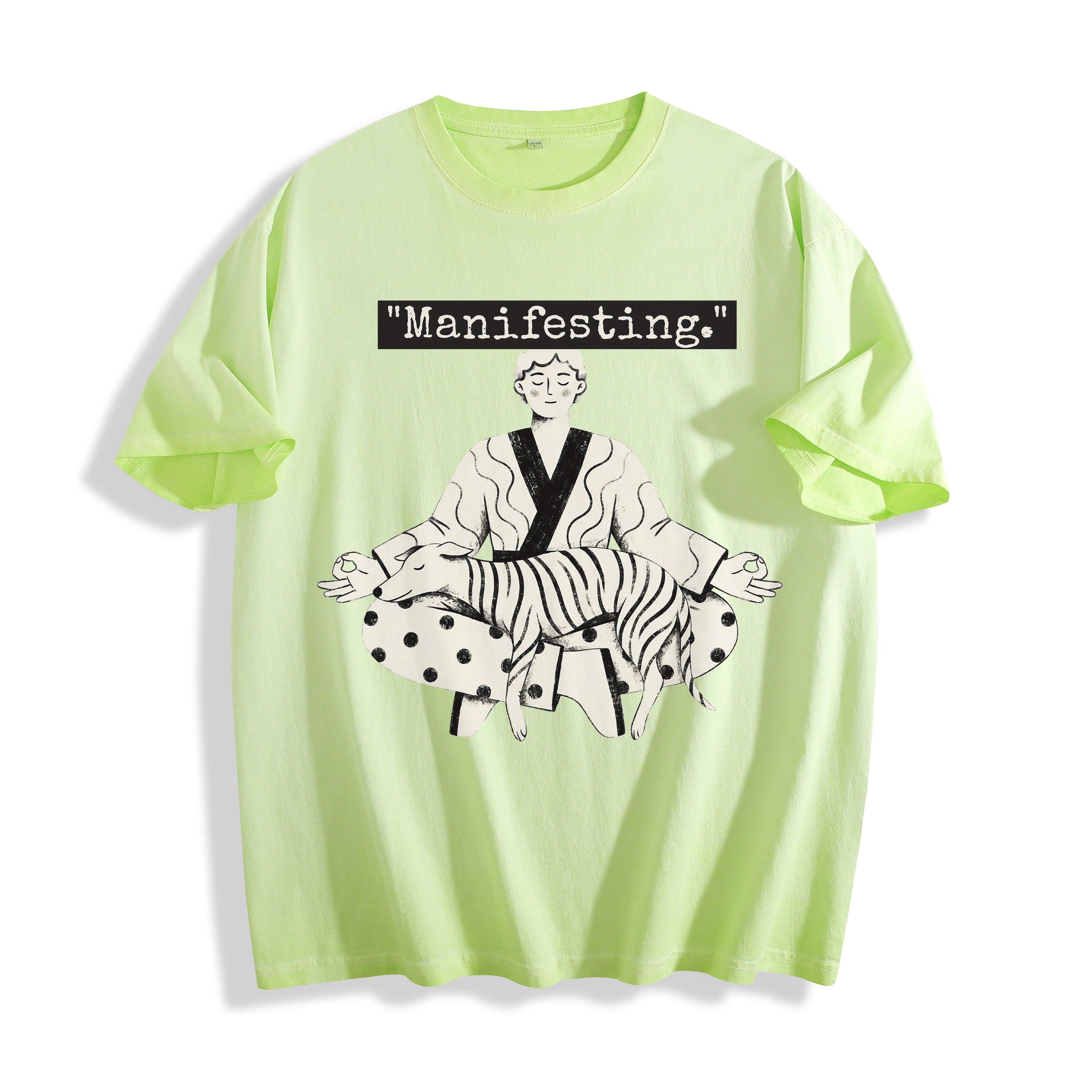 A flat lay of an acid lime manifesting meditating graphic tee, featuring the deadpan boy and dog line art print depicting a detached state of mind.