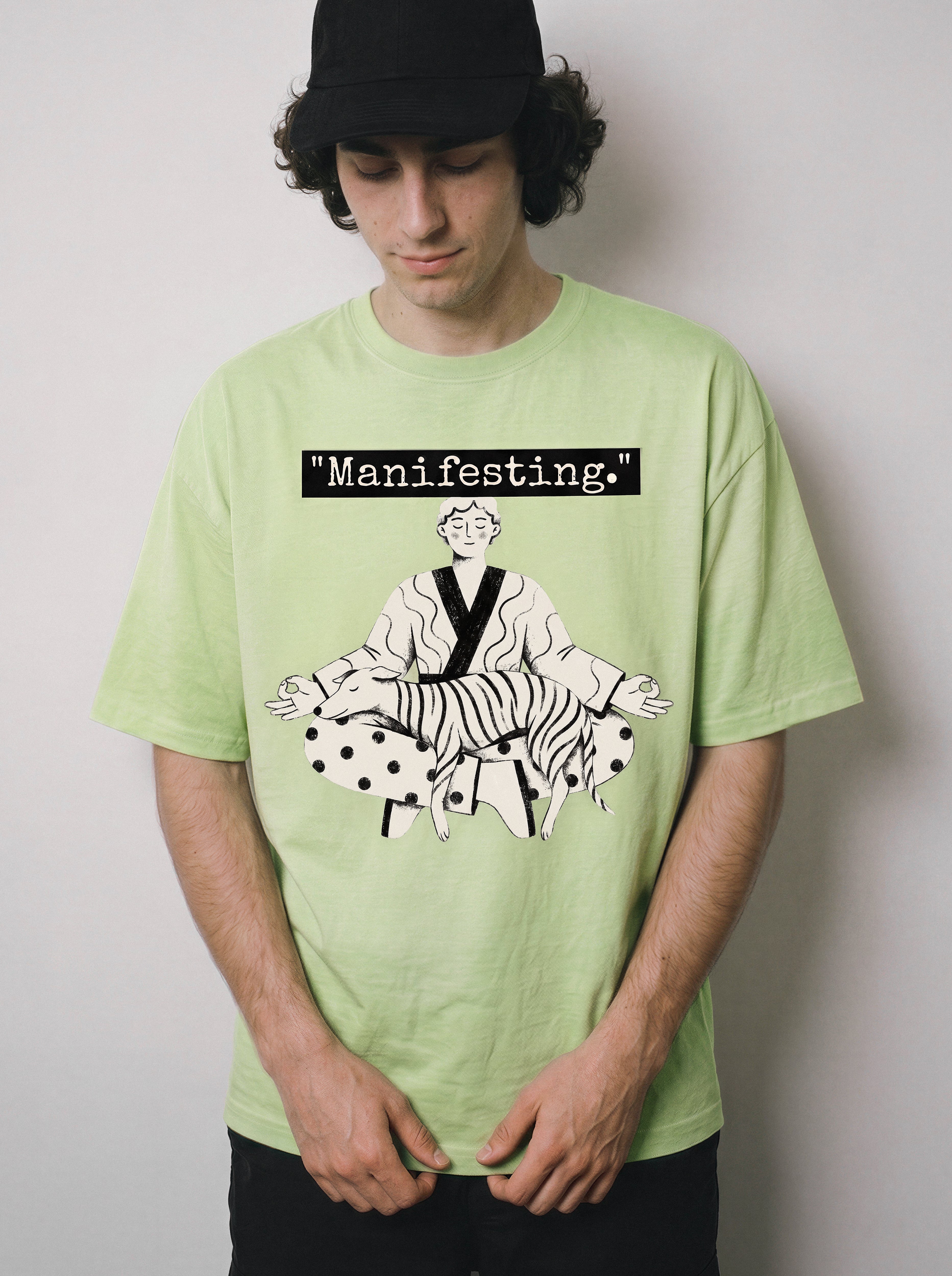 A male model looking down wearing an acid lime manifesting meditating graphic tee, capturing the minimalist apparel style and focused line art illustration.