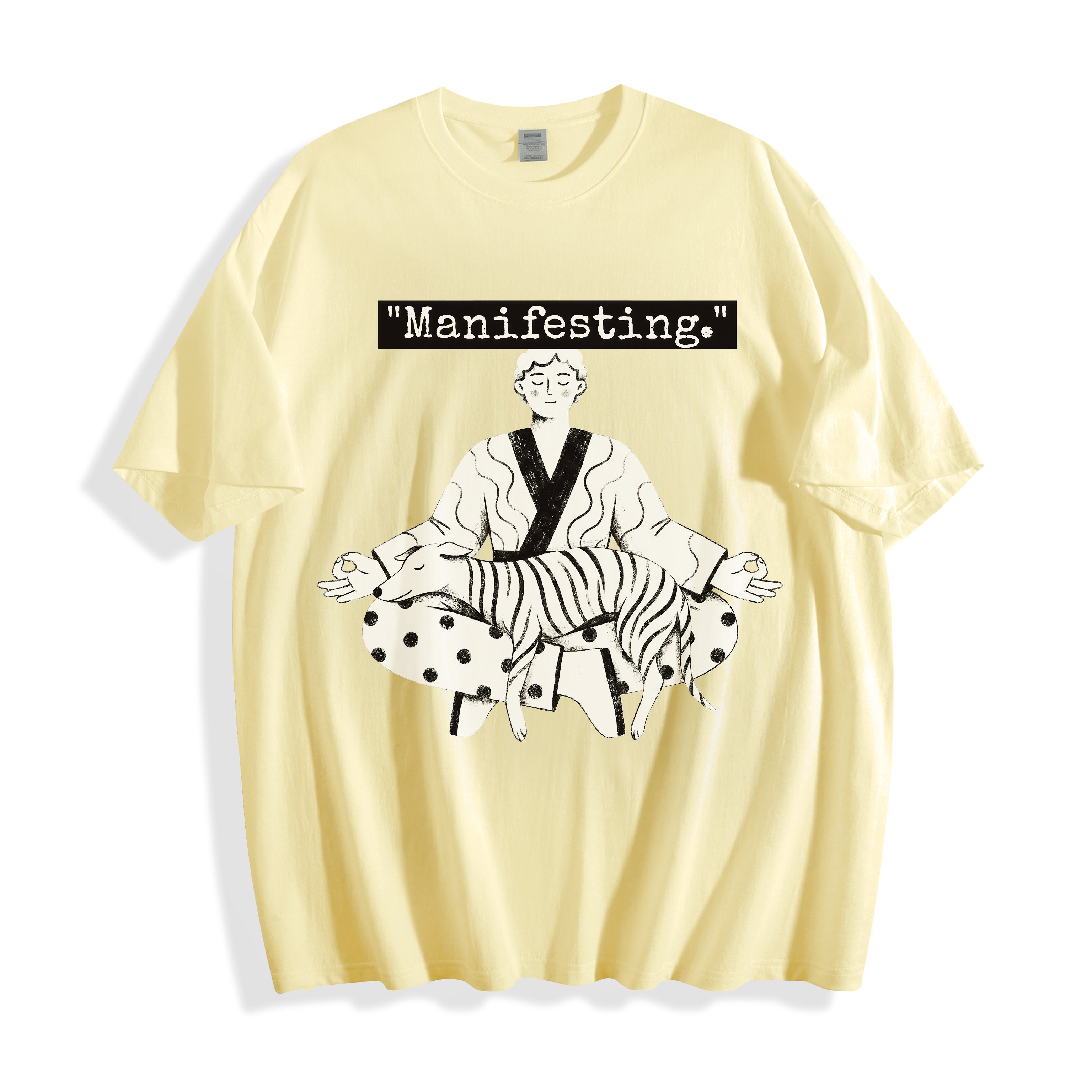 A flat lay of a butter yellow meditating boy and dog line art graphic tee, featuring the manifesting typography and crisp monochrome manga print on a clean background.