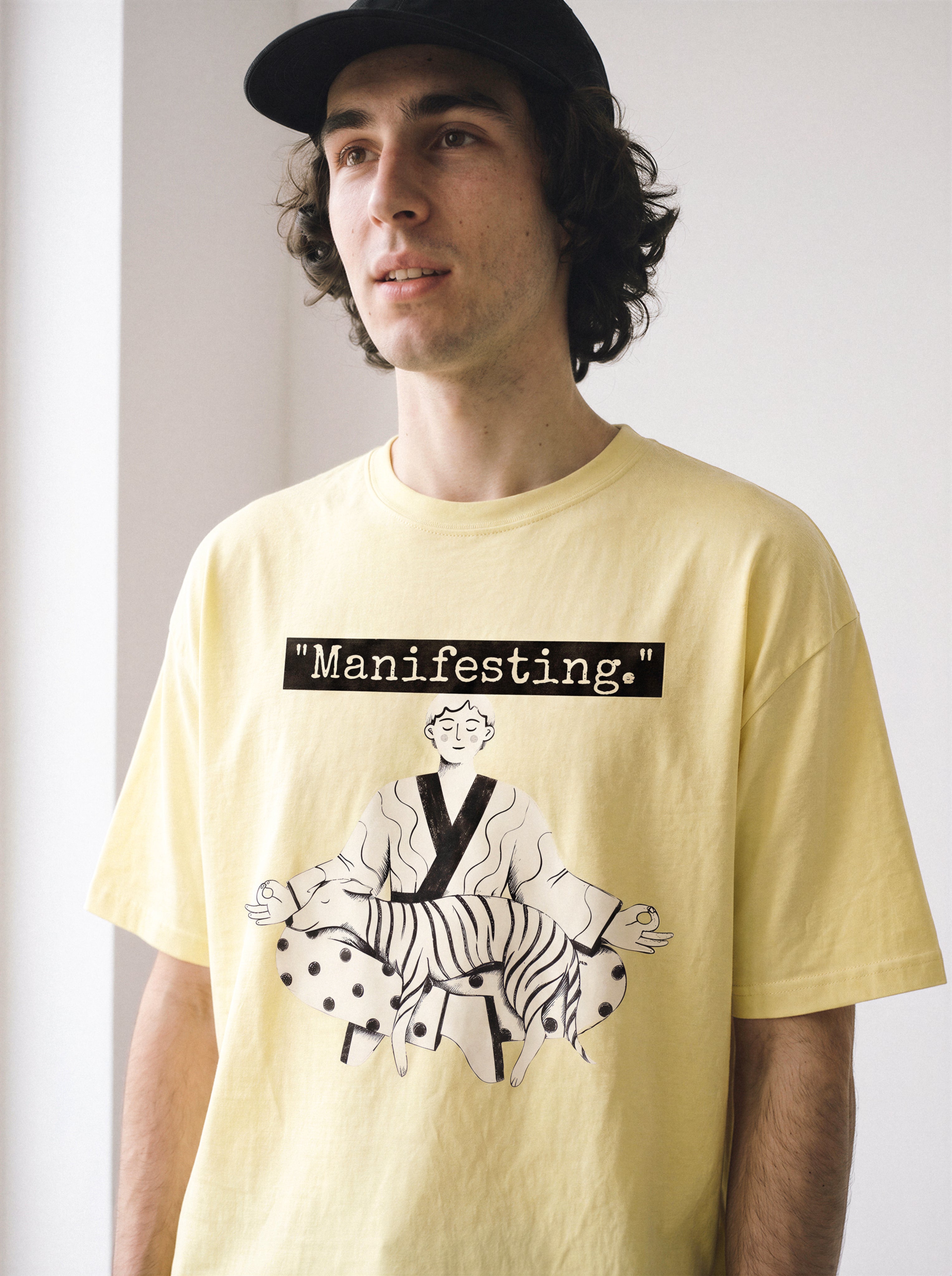 A half-body shot of a male model looking away wearing a butter yellow meditating boy and dog line art graphic tee, displaying the bold line art streetwear style.