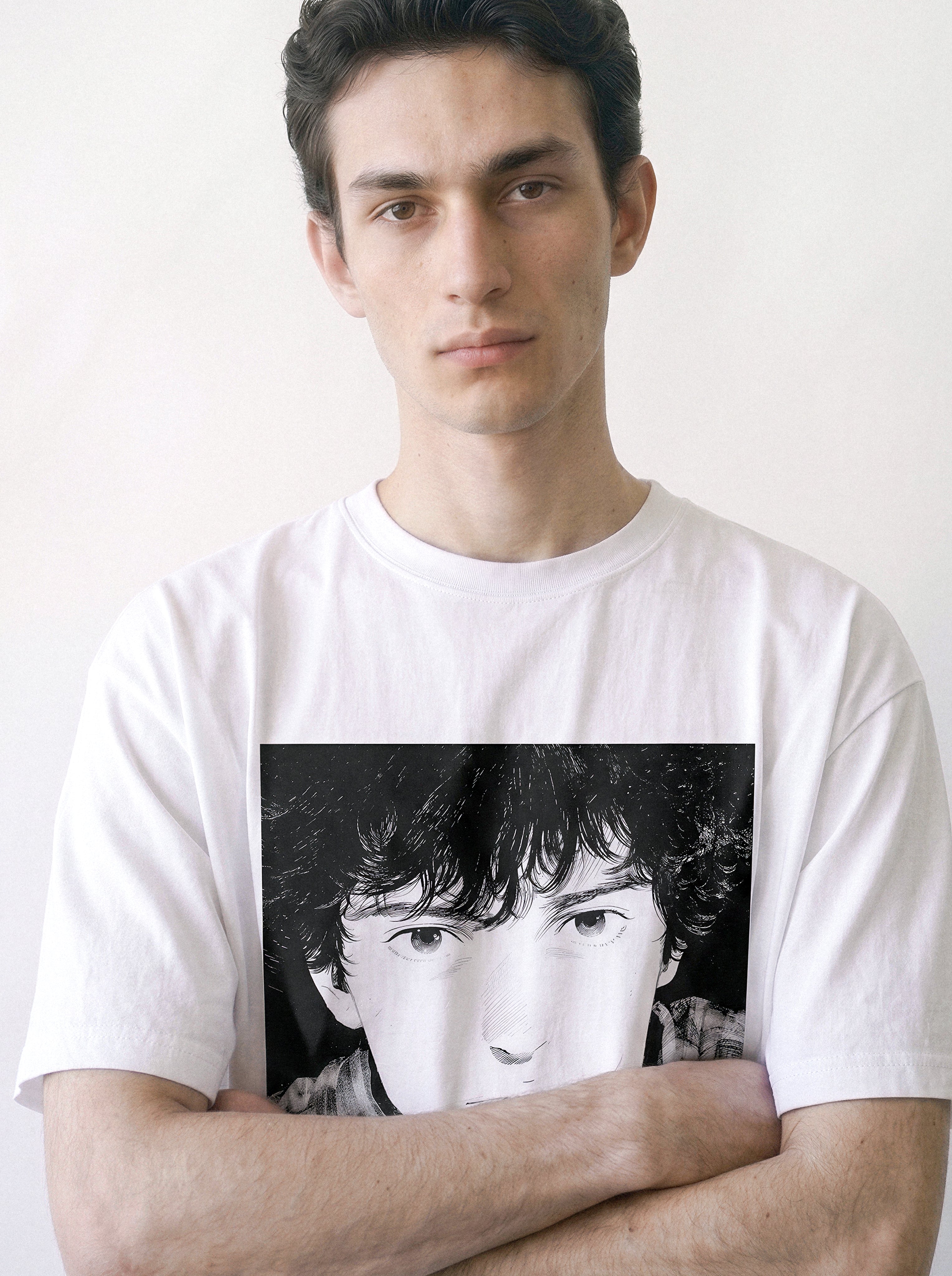 A male model with arms crossed wearing a white messy hair manga portrait graphic tee, highlighting the bold monochrome print and vintage streetwear style.