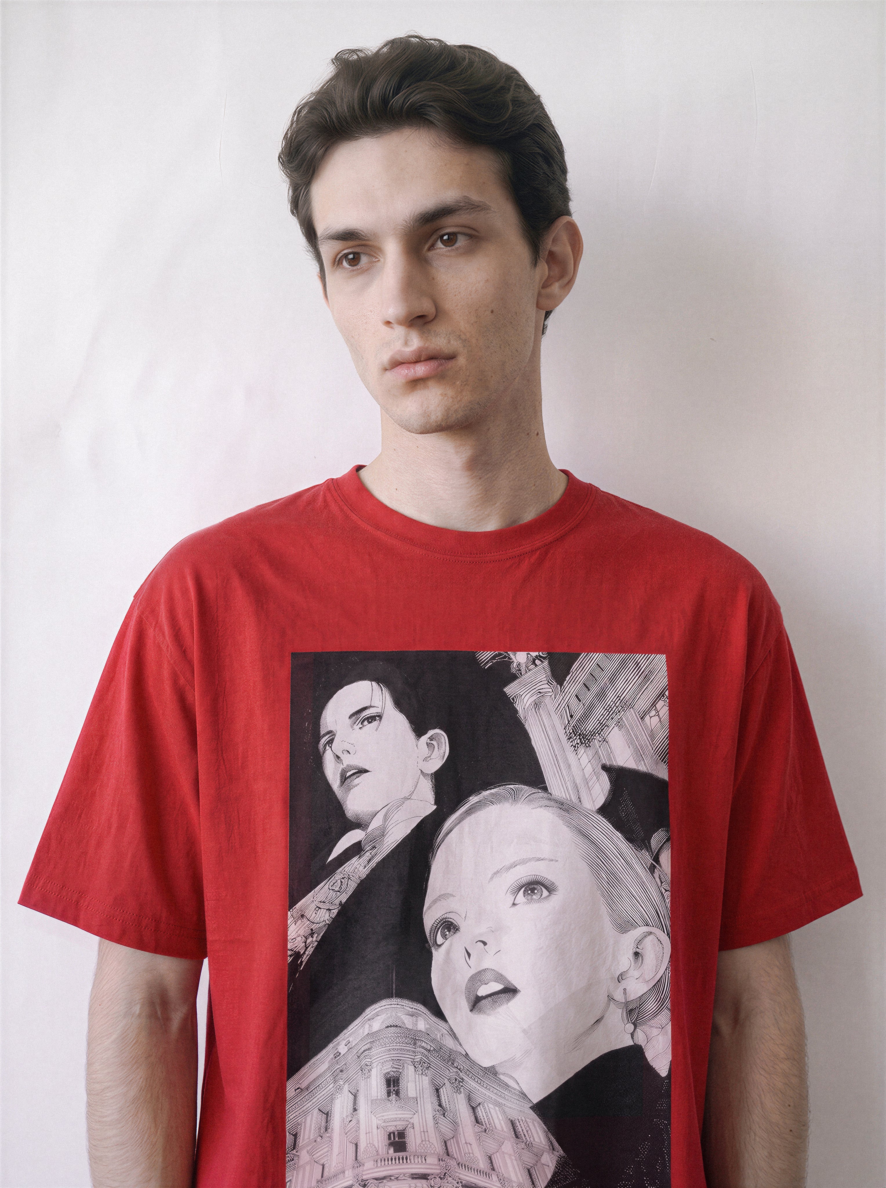 A male model looking aside wearing a red monochrome upward gaze graphic tee, displaying the intersection of two eras design and casual streetwear drape.
