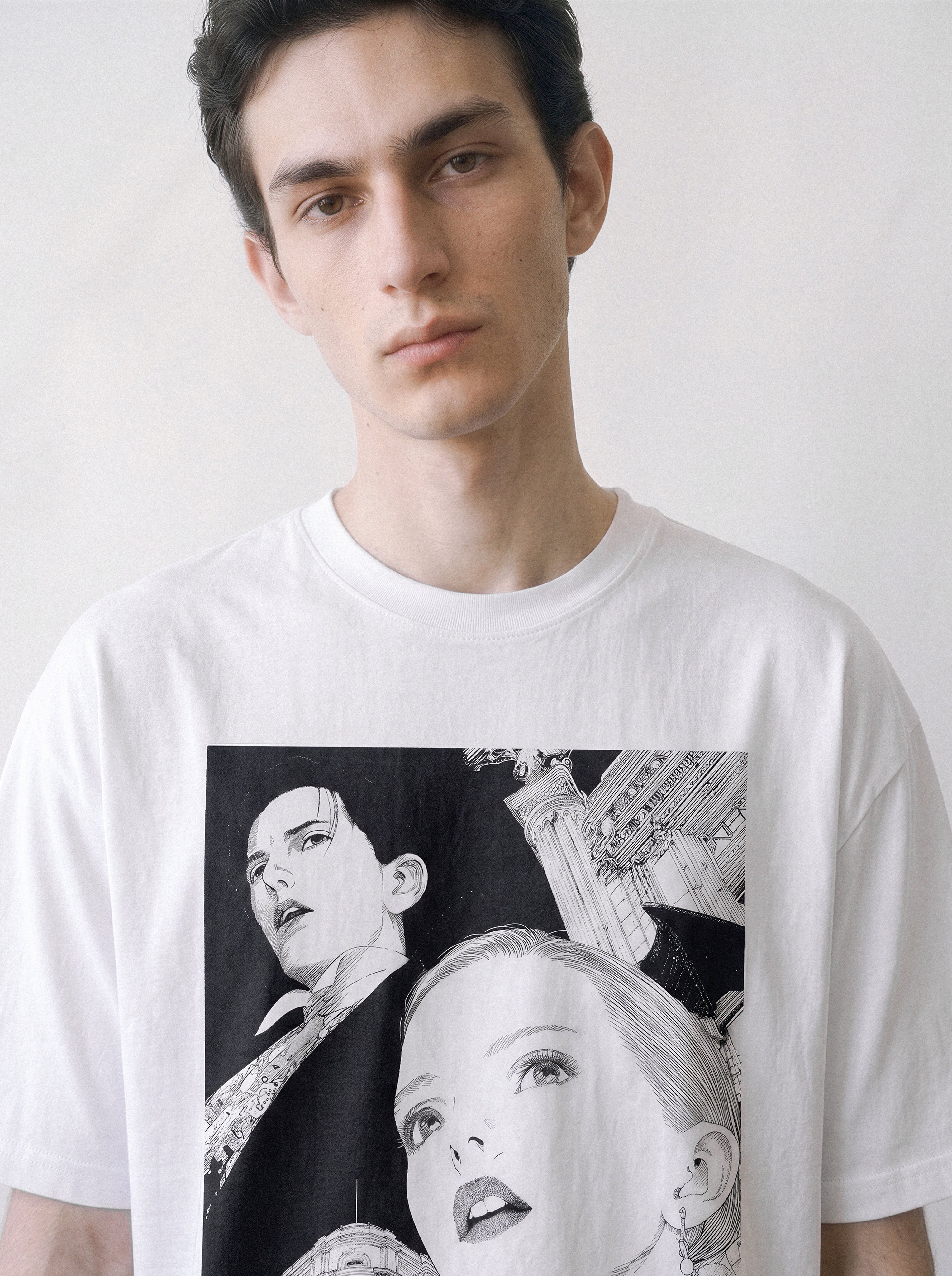 A front view of a male model wearing a white monochrome upward gaze graphic tee, showcasing the sharp monochrome lines that strip away the color interference in a relaxed boxy fit.