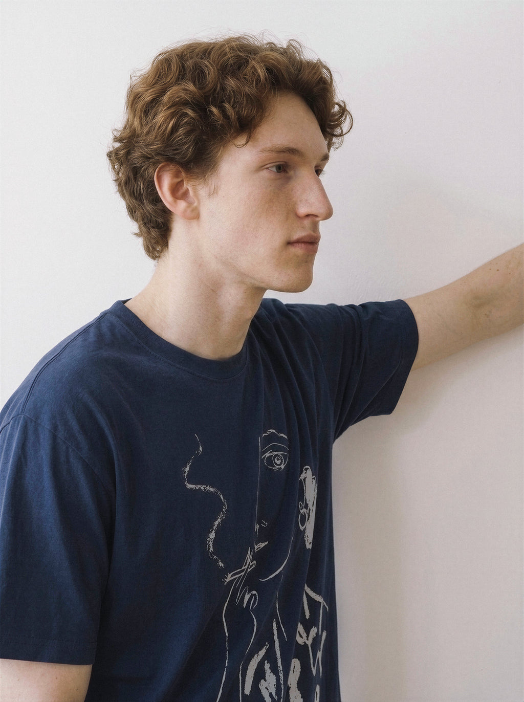 Side profile of a model looking away, demonstrating the relaxed drape of a navy oversized t-shirt featuring a modern linework smoking graphic.