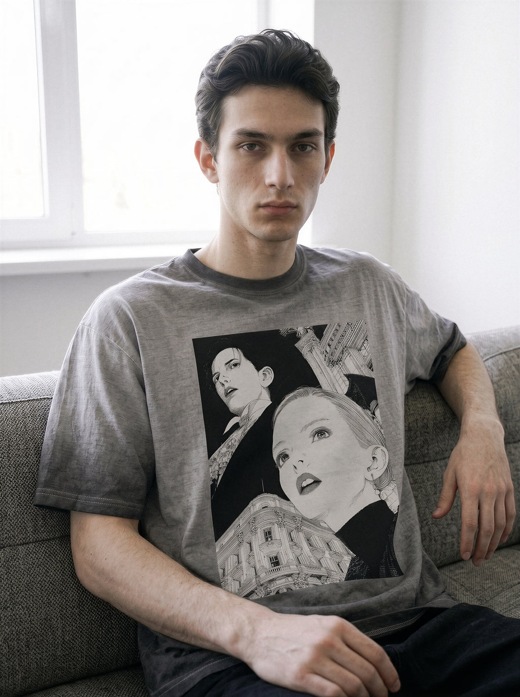 Model resting his hand on his neck while sitting, demonstrating the fit of an ombre grey retro manga graphic tee in a premium heavyweight cotton.