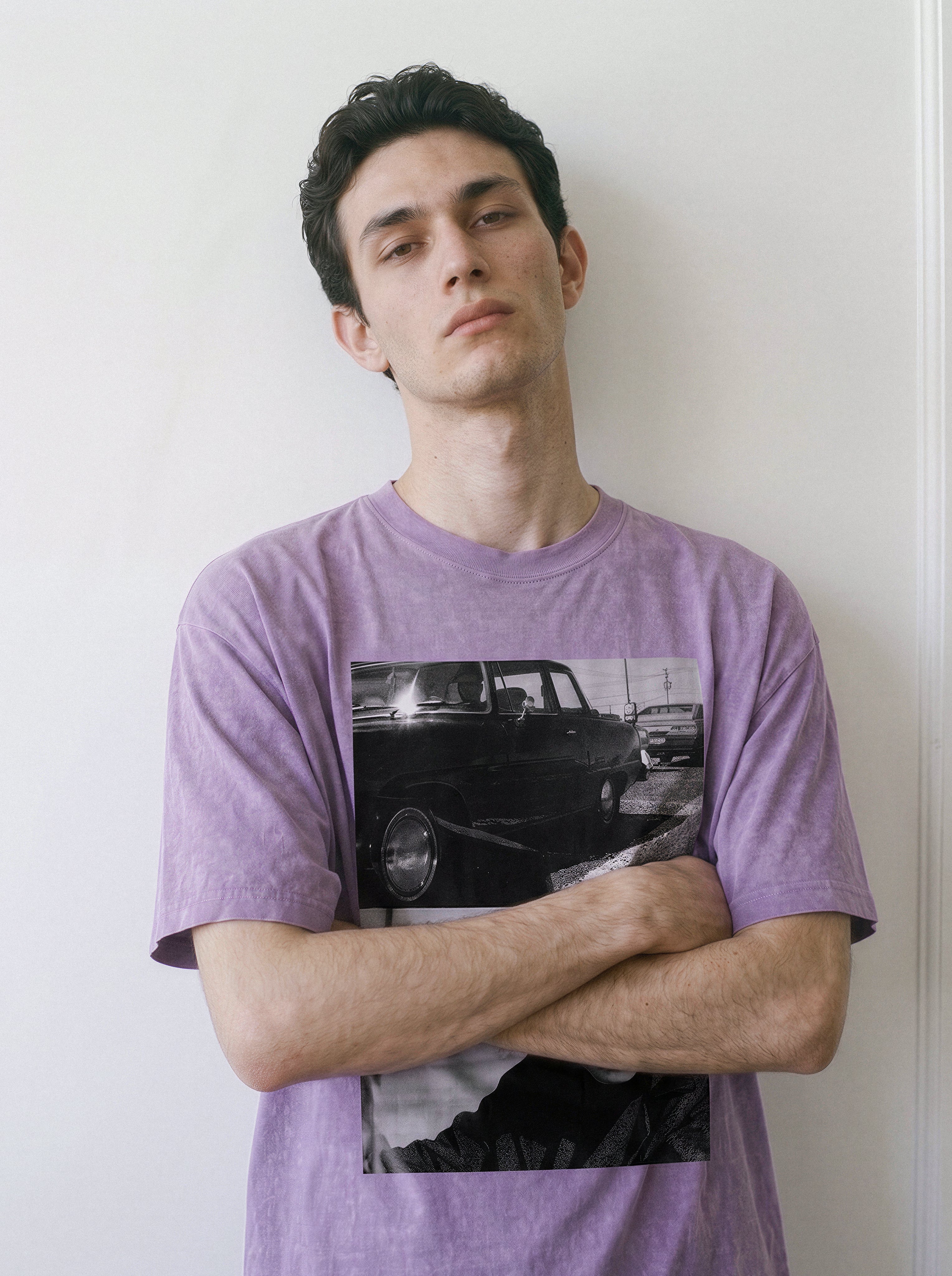 Front view of a model standing with arms crossed, demonstrating the heavyweight cotton fit of an ombre violet Yakuza aesthetic tee with a striking car and lone-wolf print.