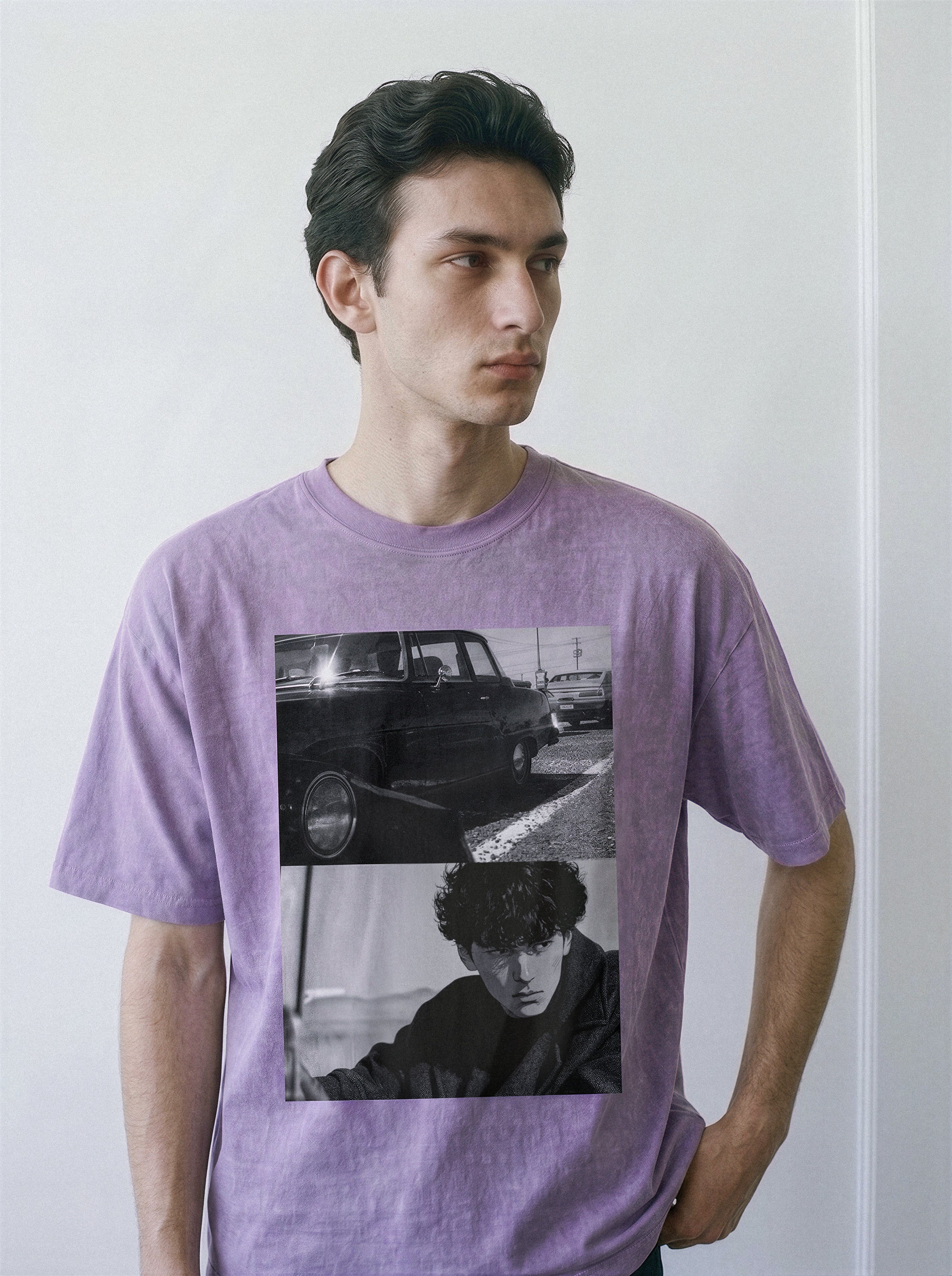 A male model looking away, wearing an ombre violet heavyweight boxy fit t-shirt featuring a 90s Yakuza cinema split-panel print of a retro car and a lone-wolf profile.