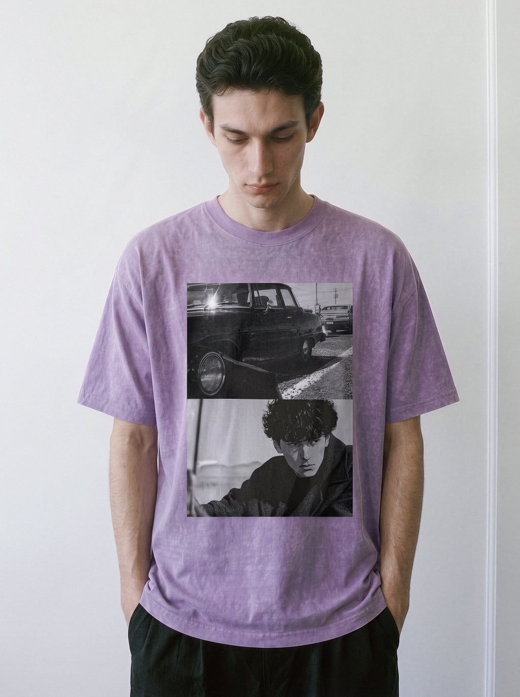 A man standing in a relaxed posture, wearing an ombre violet oversized boxy fit graphic tee featuring a gritty monochrome split-panel cinematic design.