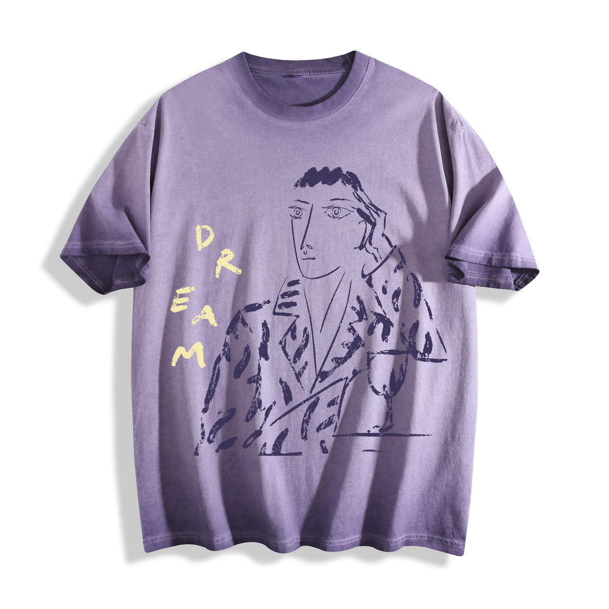 Clean flat lay product shot of an ombre violet heavyweight boxy fit t-shirt featuring a modern unshaded charcoal portrait and DREAM typography.