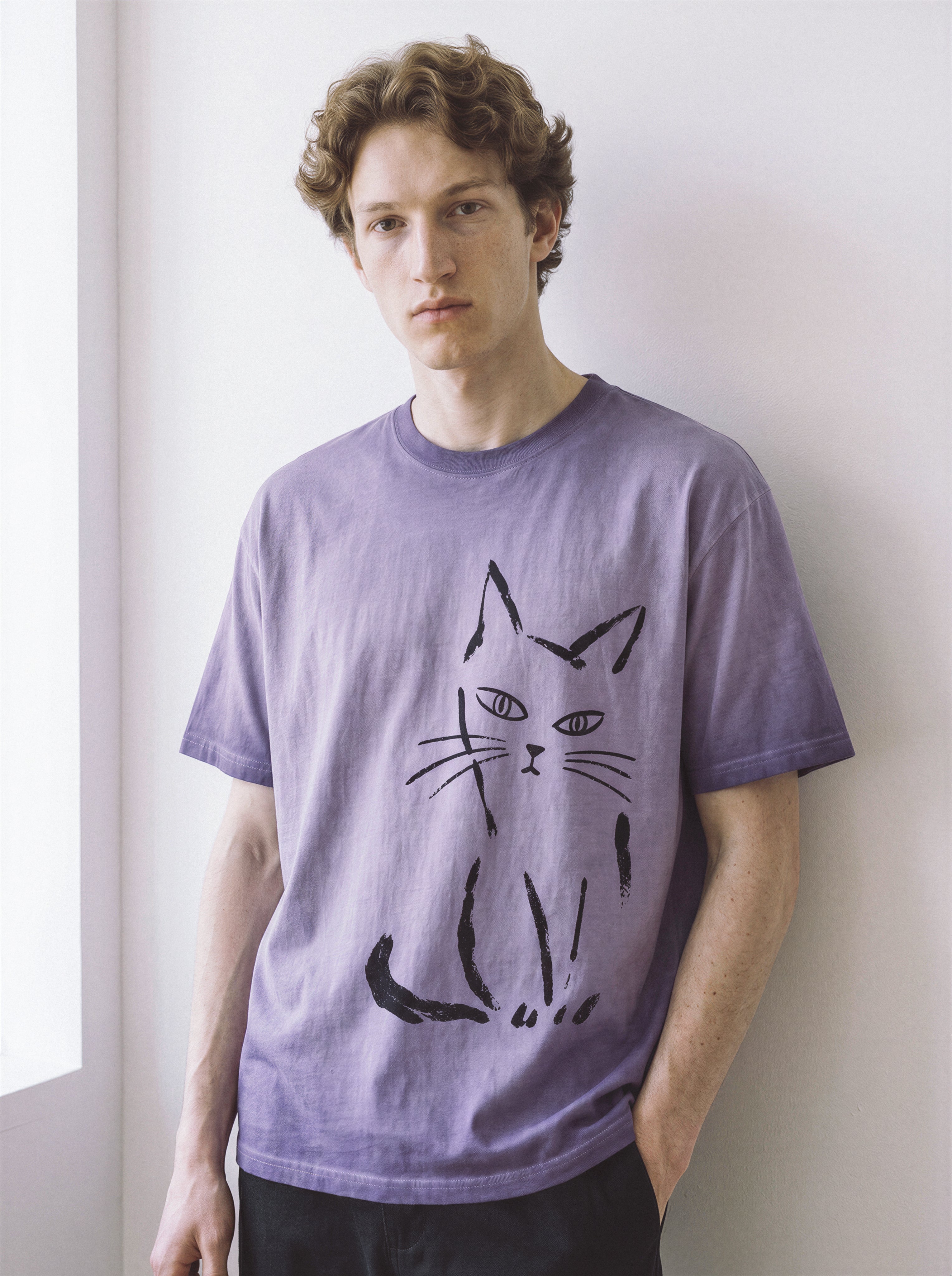 Front view of a model in a relaxed stance, demonstrating the drape of an ombre violet 230g premium cotton tee highlighting a messy paint stroke feline design.