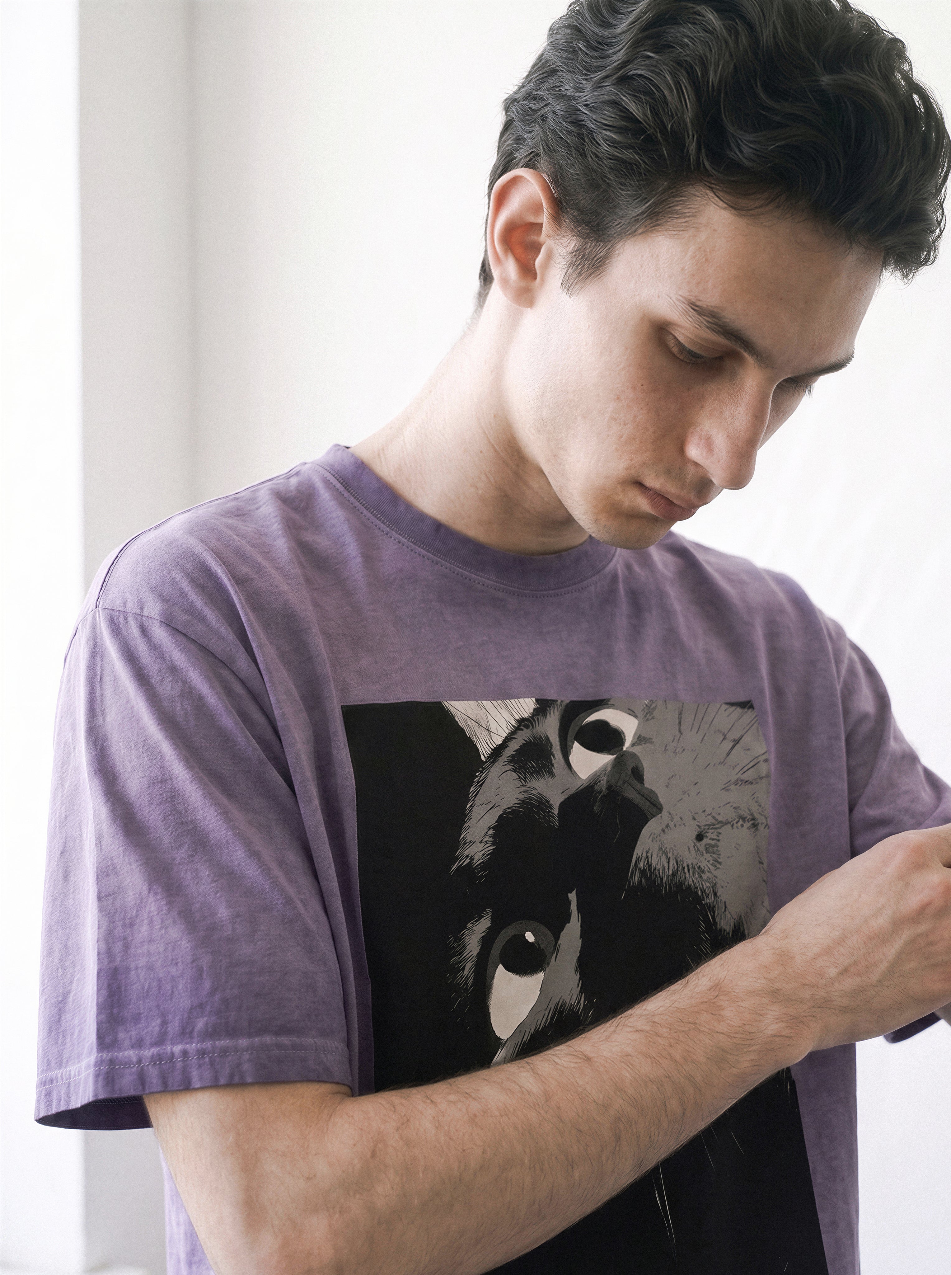 Side profile of a male model looking down and adjusting his sleeve, showcasing the comfortable 230g cotton drape of an ombre violet graphic tee.