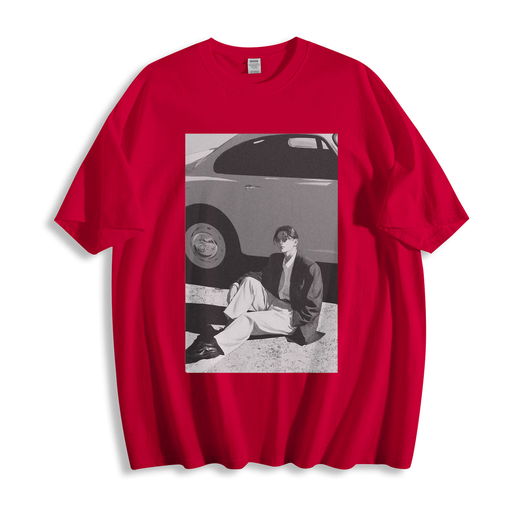 Flat lay product view of a red oversized streetwear t-shirt featuring a 90s retro cinematic black and white photography print, showing a person sitting next to a car. 