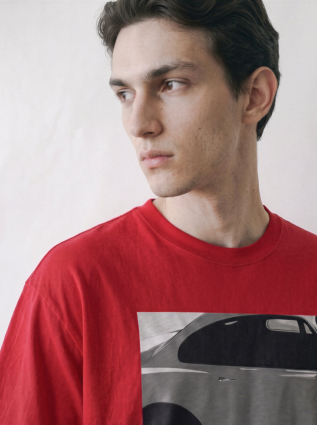 Close-up shot of a model looking right, highlighting the neckline and shoulder structure of a red 90s retro cinematic graphic t-shirt.