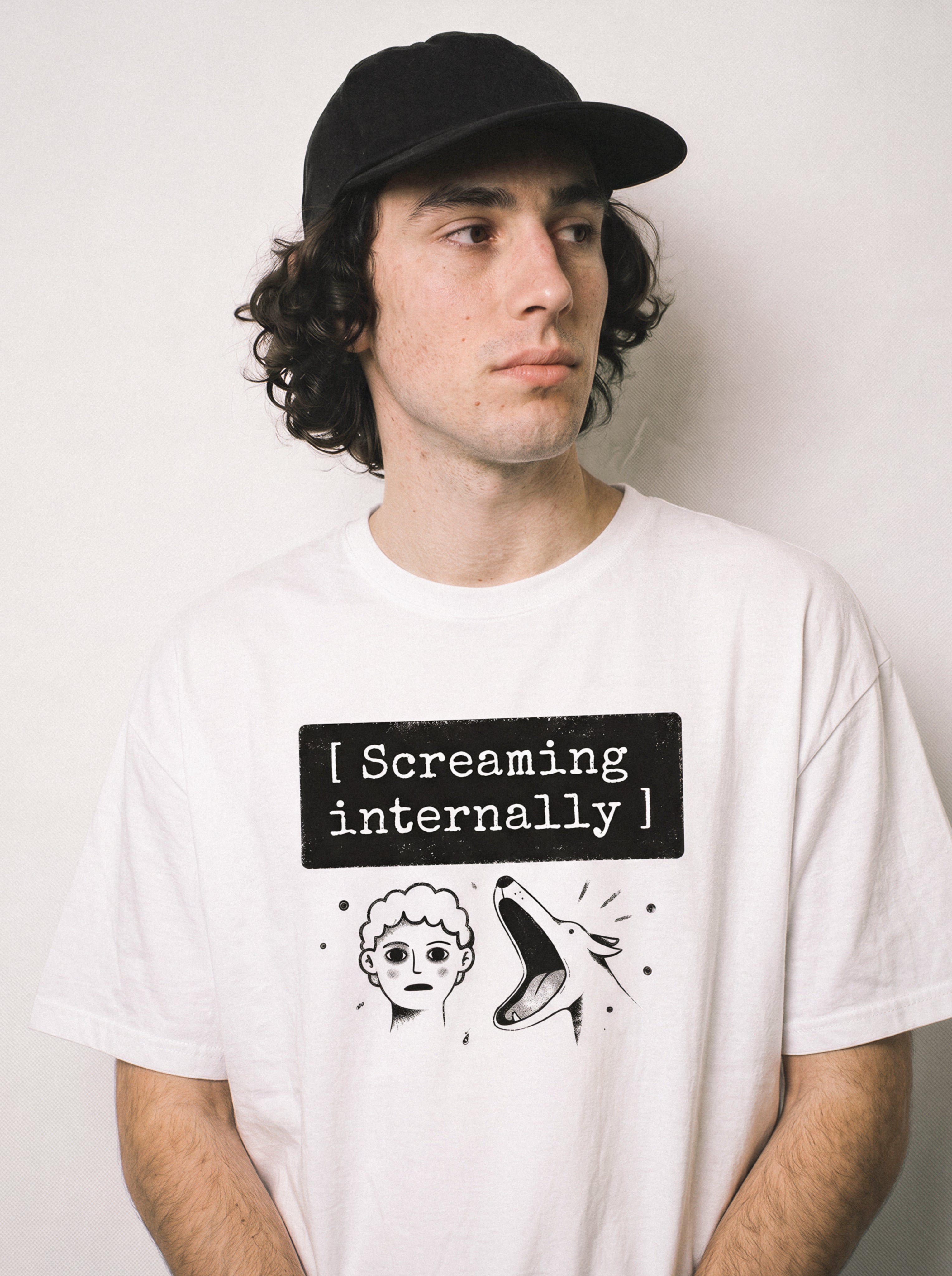 A close-up of a male model wearing a white screaming internally psychological graphic tee, showcasing the text box typography and zero-emotions vibe.