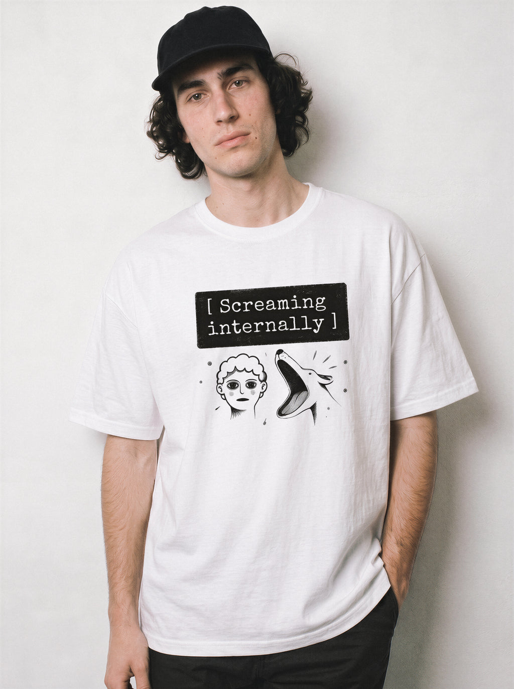A male model with hands in pockets wearing a white screaming internally psychological graphic tee, highlighting the cool on the outside aesthetic and relaxed boxy fit.