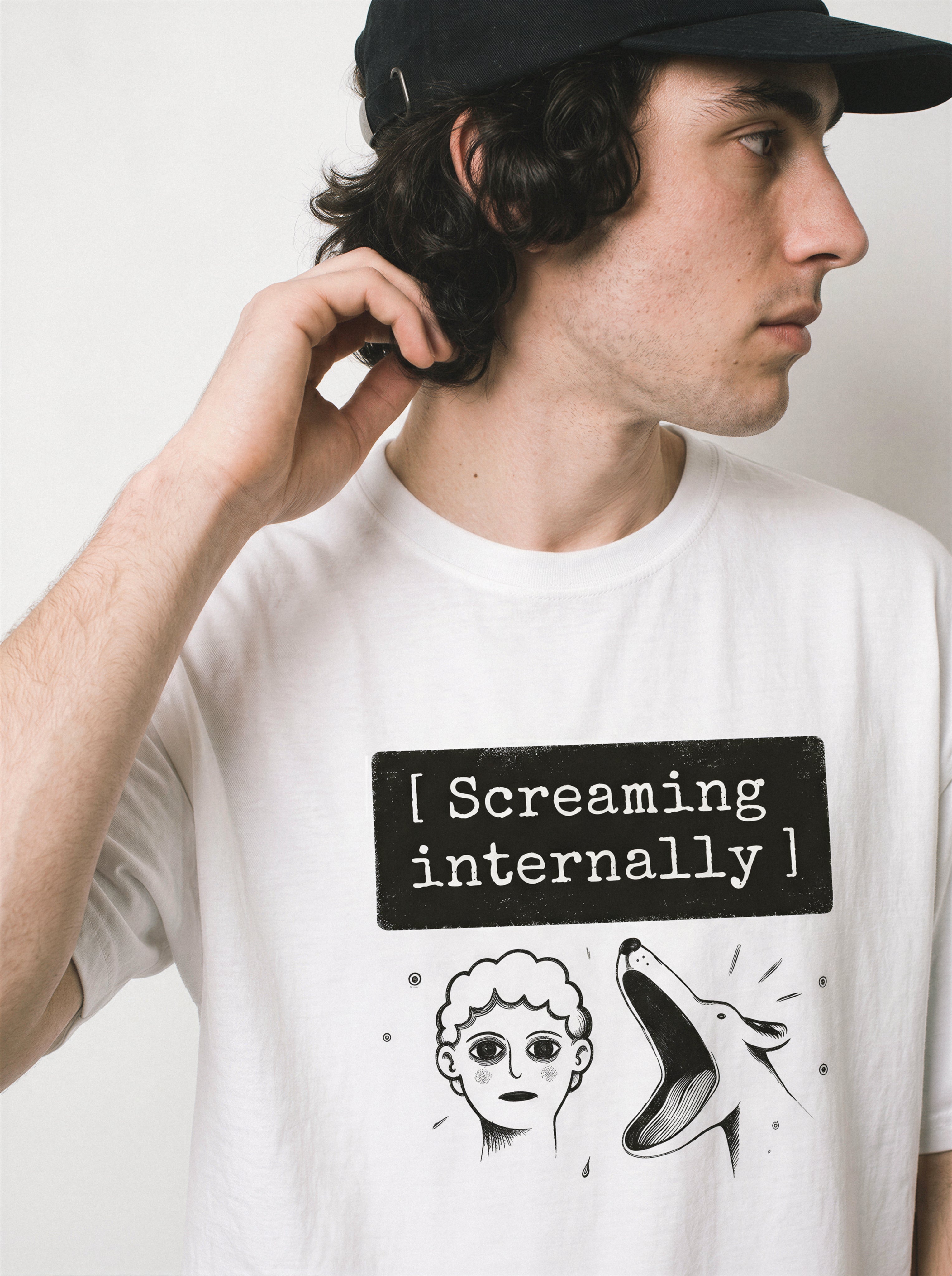 A profile view of a male model touching his neck wearing a white screaming internally psychological graphic tee, capturing the introvert psychological streetwear style and internal meltdown mood.