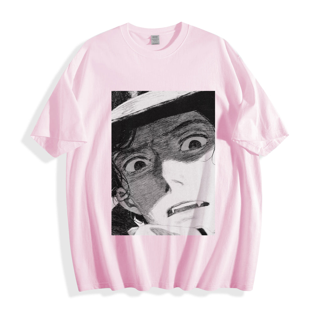 A flat lay of a light pink shocked face manga panel graphic tee, displaying the high-contrast monochrome retro manga illustration on a soft pastel base.