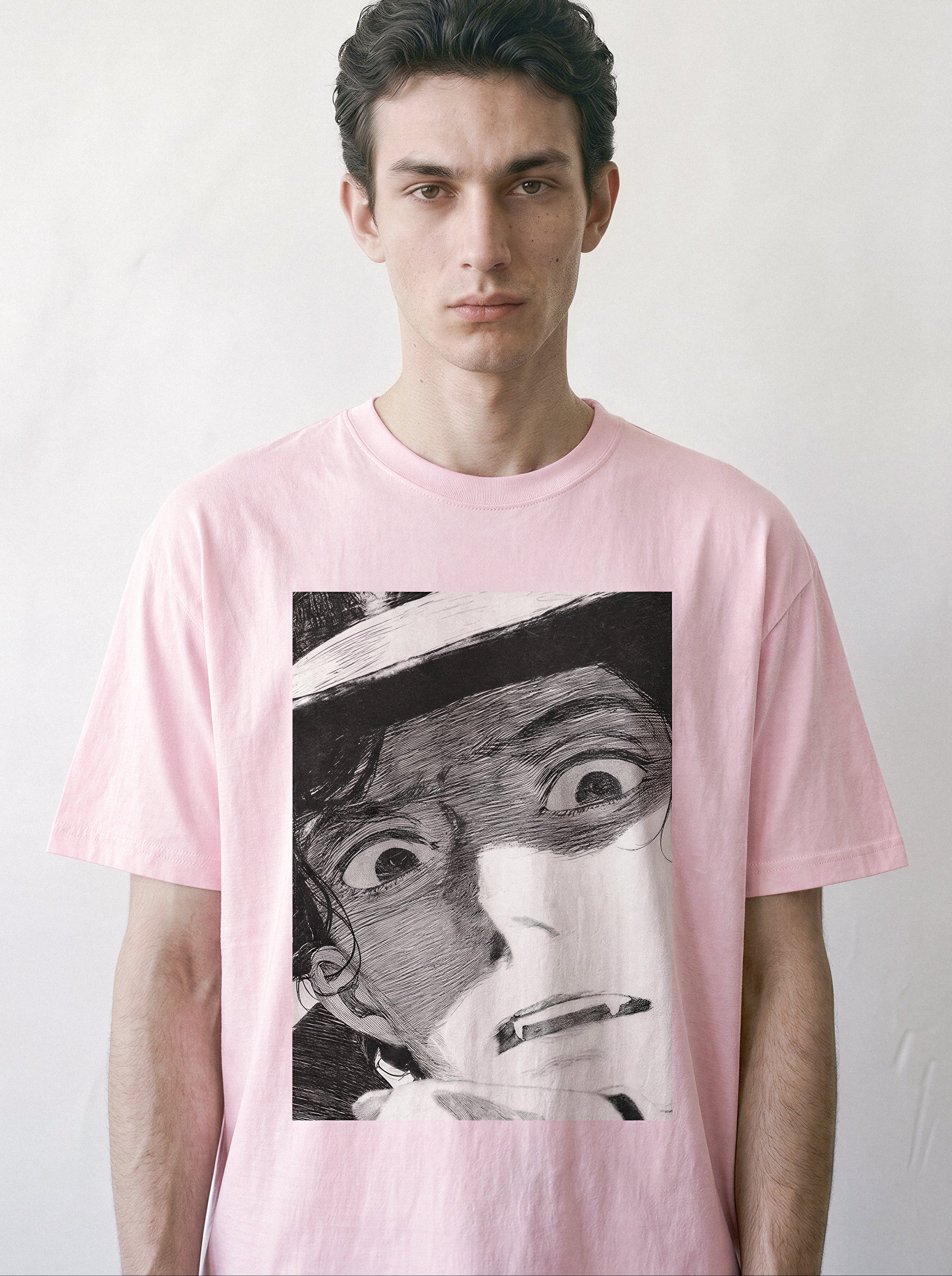 A front view of a male model wearing a light pink shocked face manga panel graphic tee, showcasing the high-contrast retro anime illustration and relaxed unisex fit.