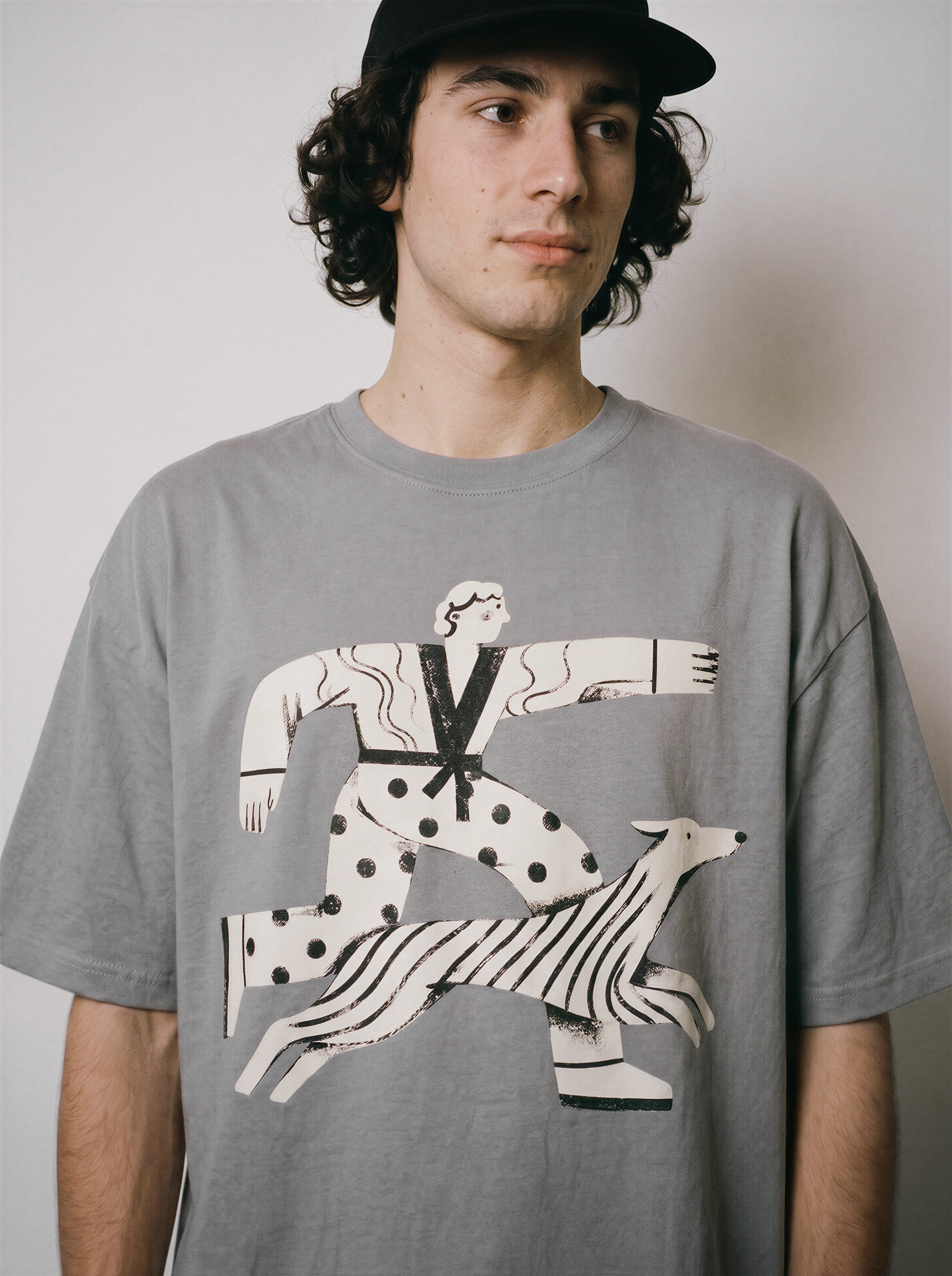 A close-up of a male model wearing a gray striding away line art graphic tee, showcasing the person and dog striding forward with absolute conviction.