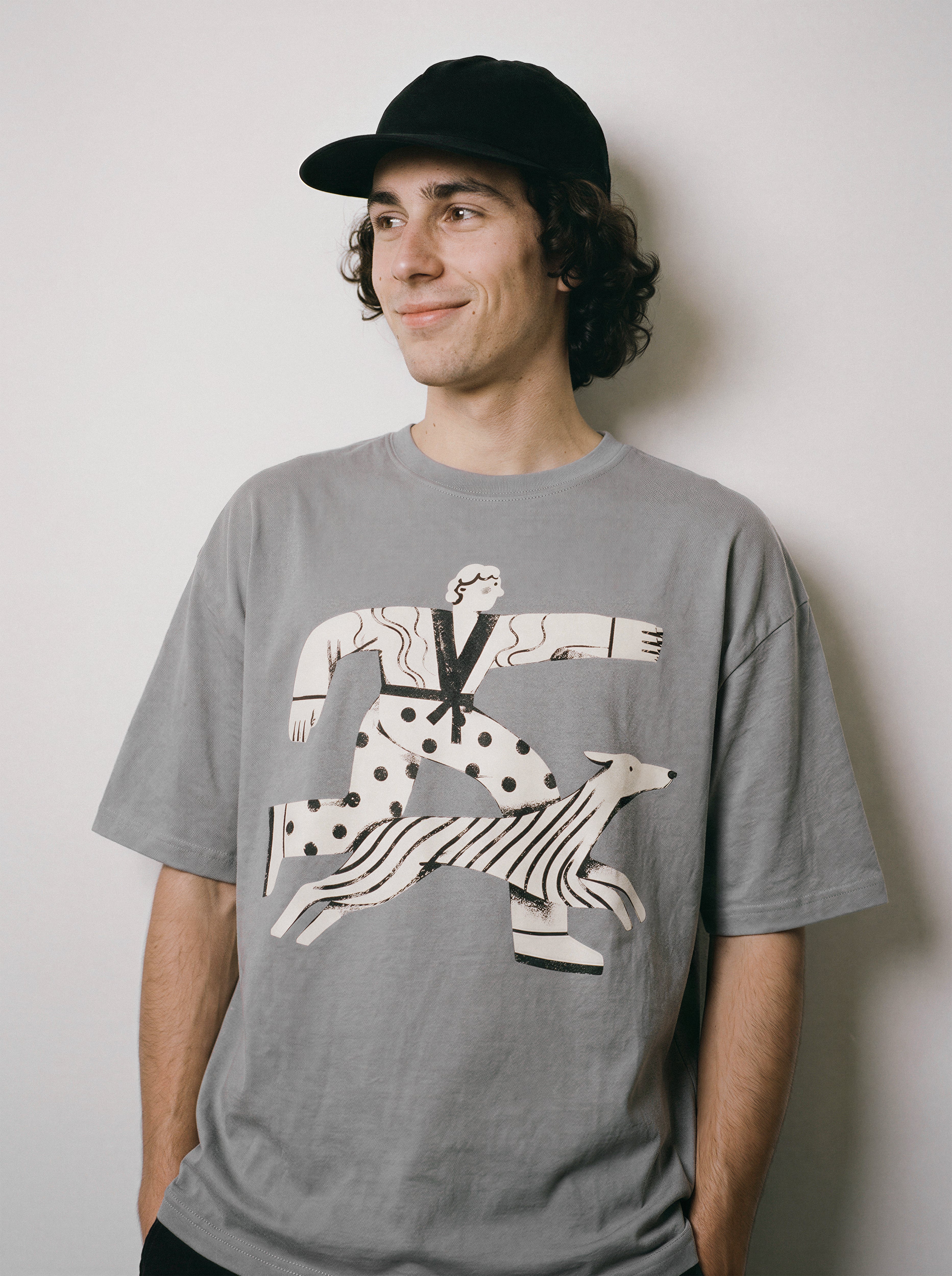 A male model smiling and looking right wearing a gray striding away line art graphic tee, conveying the conviction mindset that problems can't catch me.