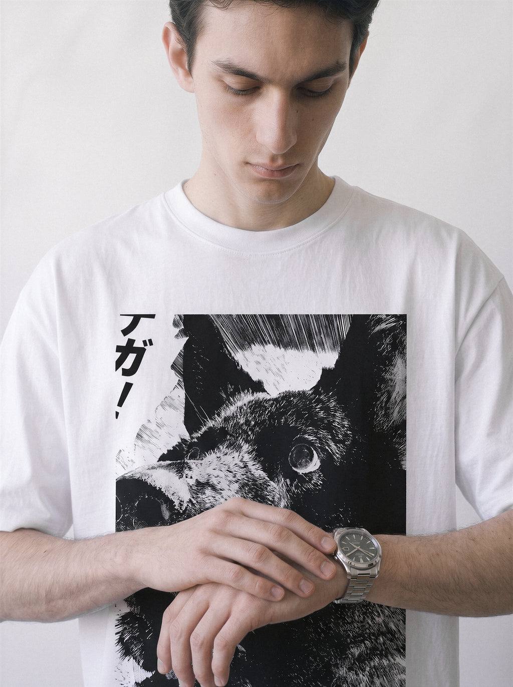 A male model looking down at his watch wearing a white surprised dog comic panel graphic tee, highlighting the katakana sound effect and ink manga style.