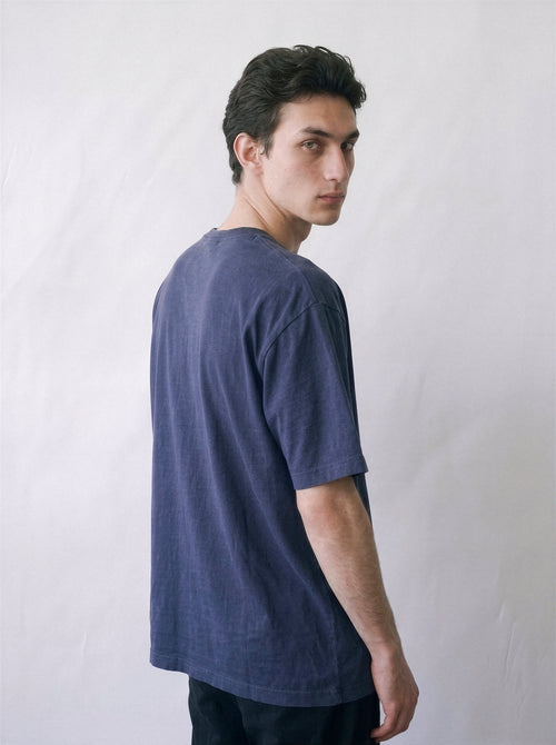 A male model looking over his shoulder wearing a vintage navy 90s monochrome motorcycle photography tee, highlighting the gritty analog sportbike print on the back.