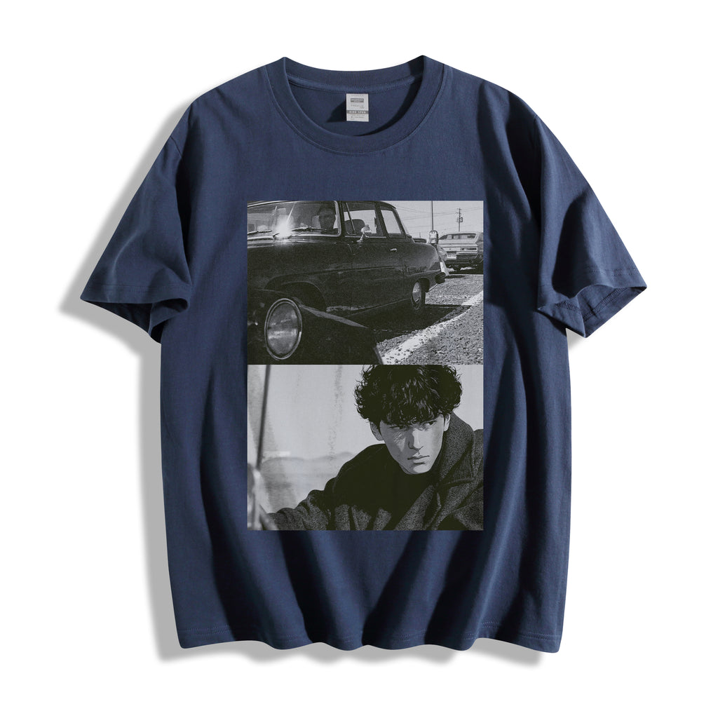 A navy blue short-sleeve t-shirt with a black and white graphic print on the front showing a vintage car and a portrait of a man, highlighting a gritty 90s monochrome split-panel cinematic print.displayed against a clean white background.