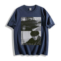A navy blue short-sleeve t-shirt with a black and white graphic print on the front showing a vintage car and a portrait of a man, highlighting a gritty 90s monochrome split-panel cinematic print.displayed against a clean white background.