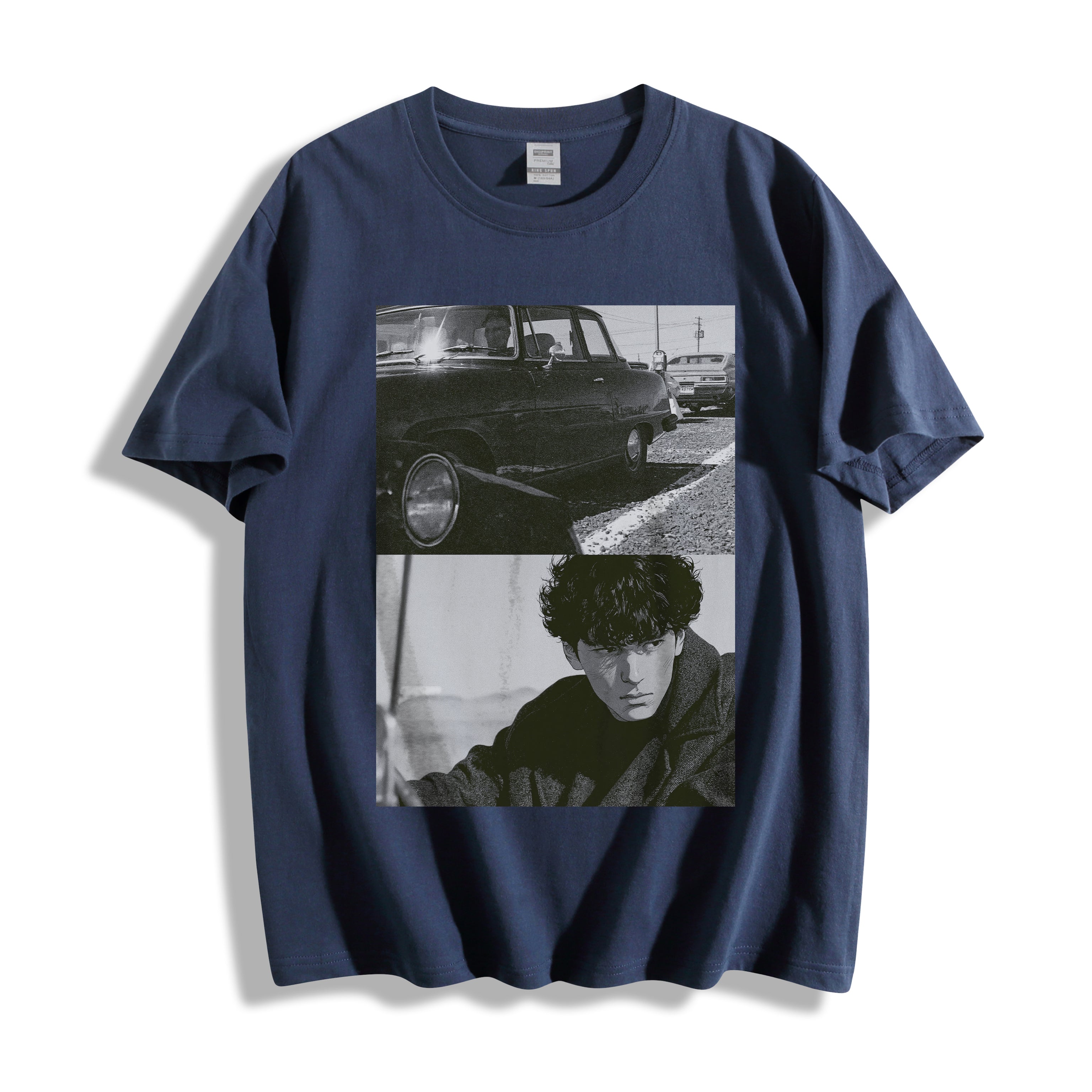 A navy blue short-sleeve t-shirt with a black and white graphic print on the front showing a vintage car and a portrait of a man, highlighting a gritty 90s monochrome split-panel cinematic print.displayed against a clean white background.