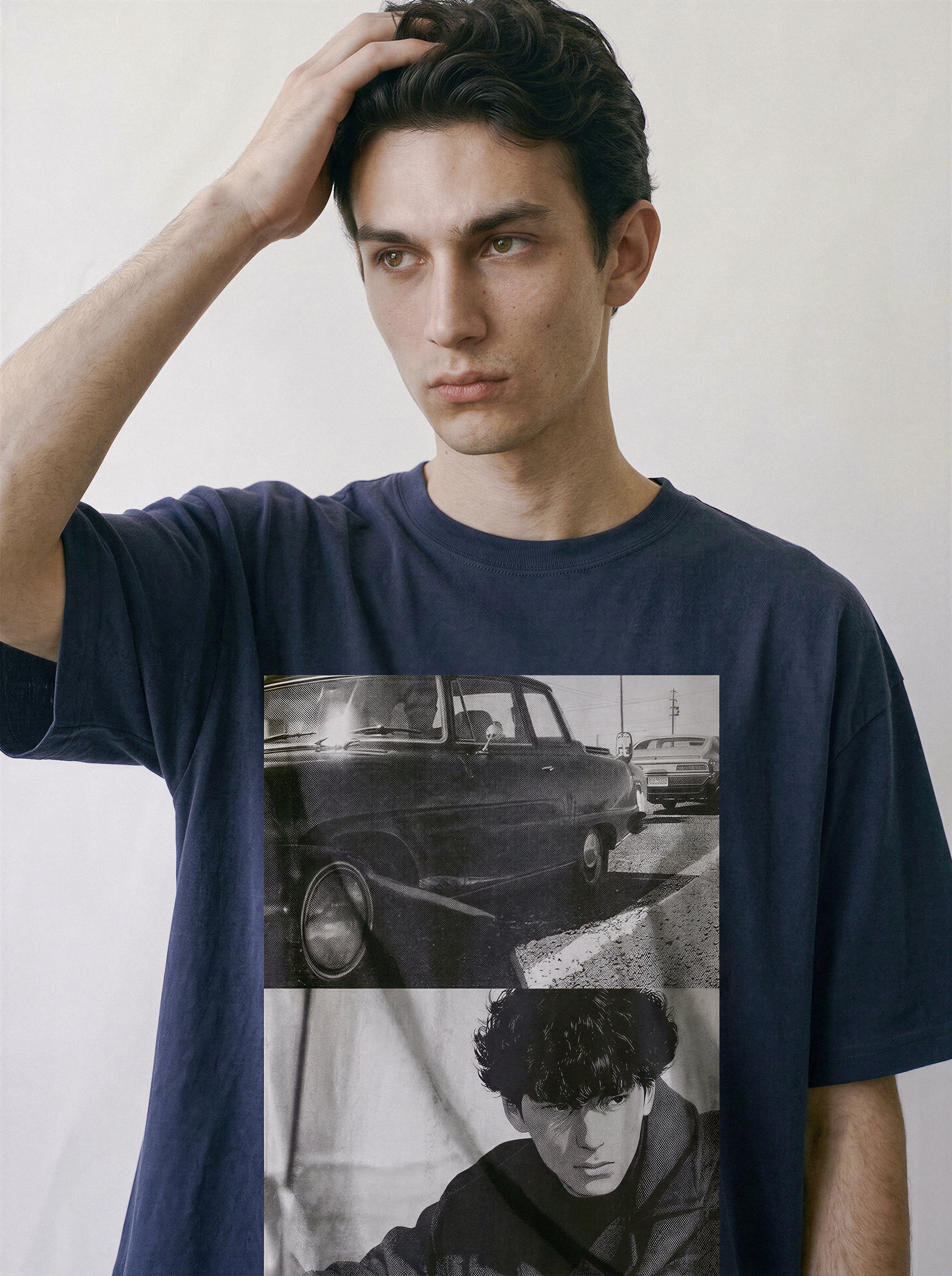 A male model resting his hand on his head, wearing a vintage navy 90s retro photography t-shirt featuring a gritty street realism car and silhouette print.