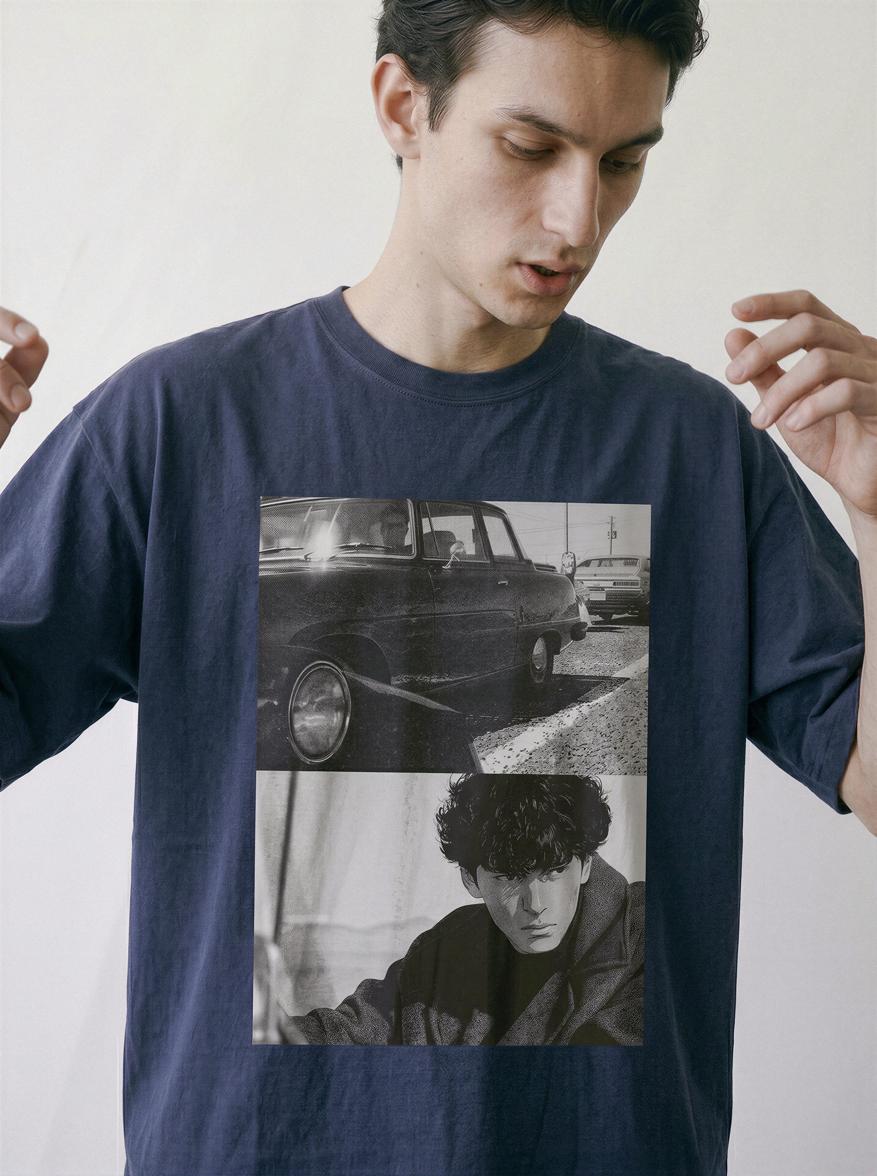 Model slightly adjusting his shirt, highlighting the drop-shoulder cut of a vintage navy oversized tee with a 90s hardboiled split-panel graphic.