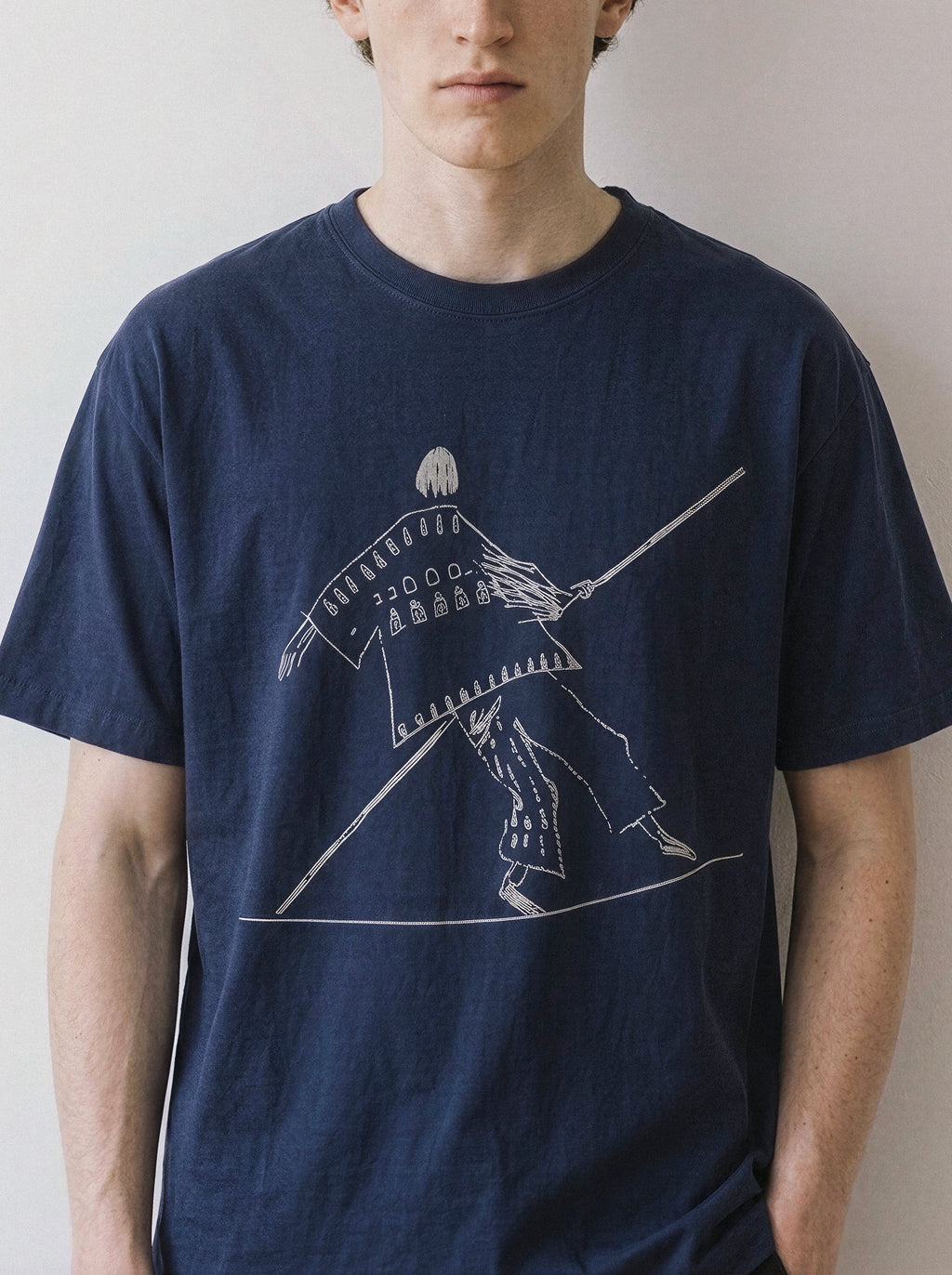 Front view of a male model wearing a vintage navy oversized t-shirt, highlighting the minimalist high wire tightrope walker line art design.